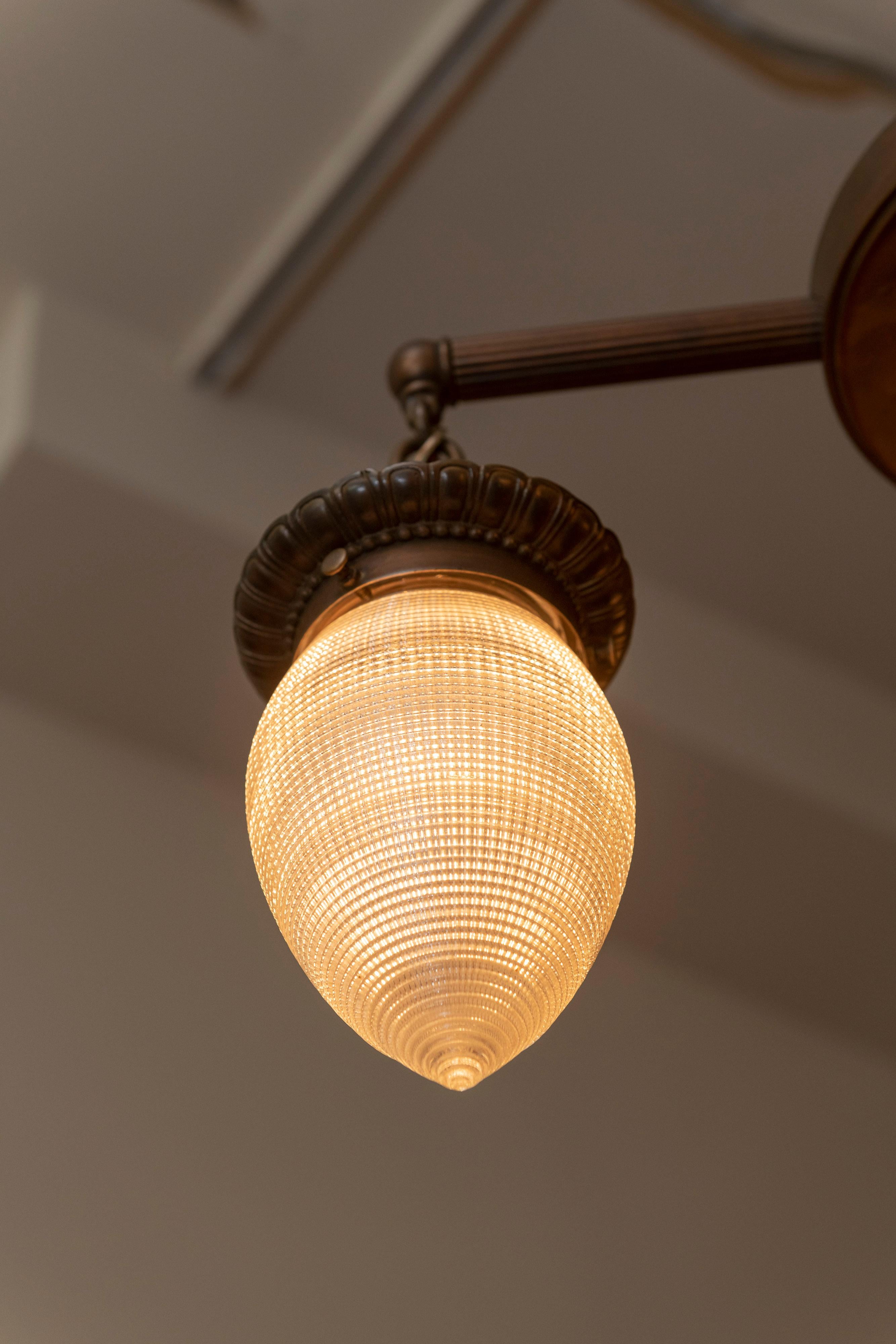 This very handsome chandelier combines simplicity with function, circa 1910. Clean lines on the metalwork and rare and wonderful glass shades by 