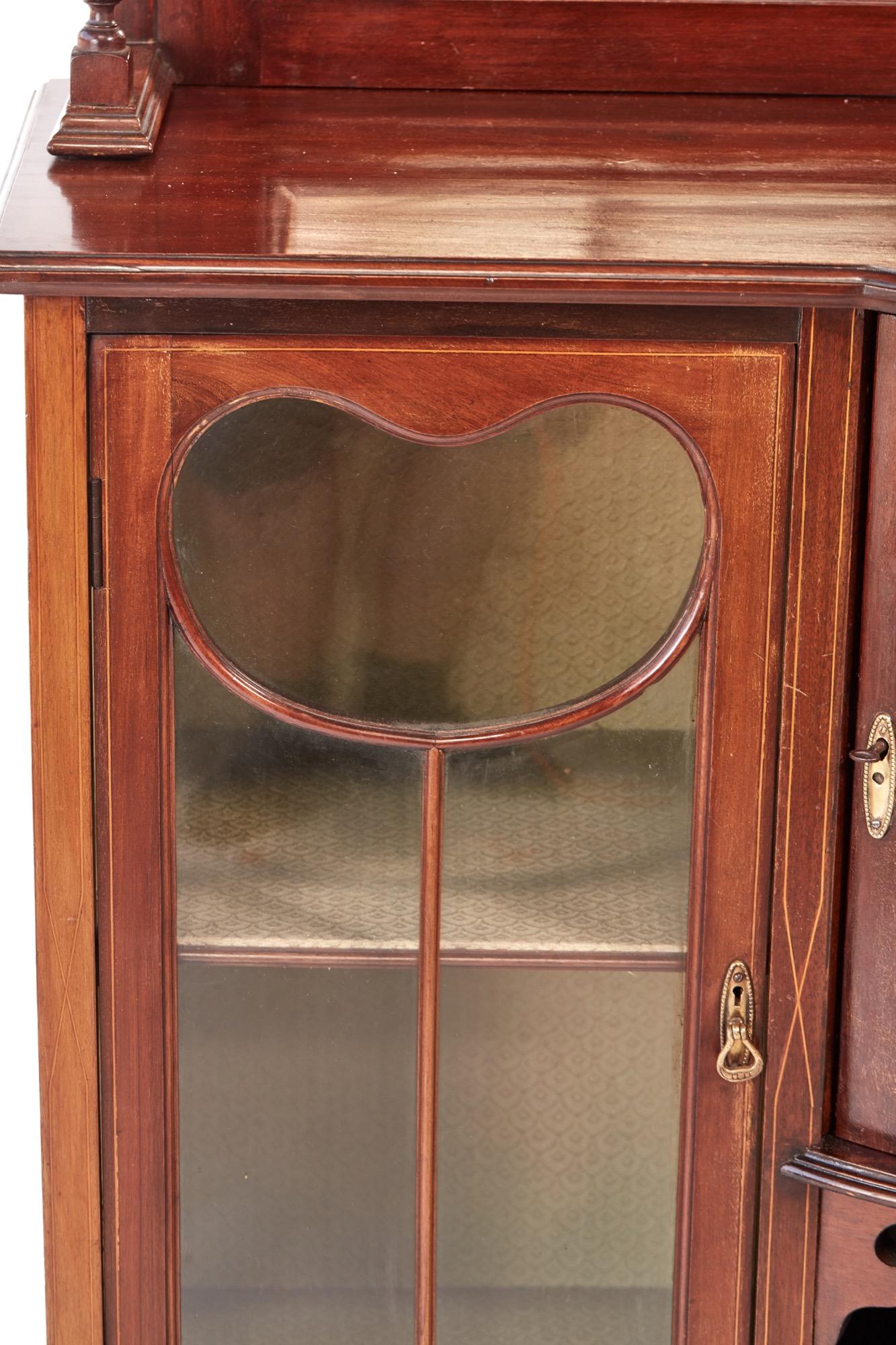 Edwardian inlaid mahogany display cabinet, having a shaped inlaid top with three beveled edge mirrors and one shaped shelf supported by turned columns, the base having a lovely mahogany top, two glazed doors, one bow front door with satinwood inlay,