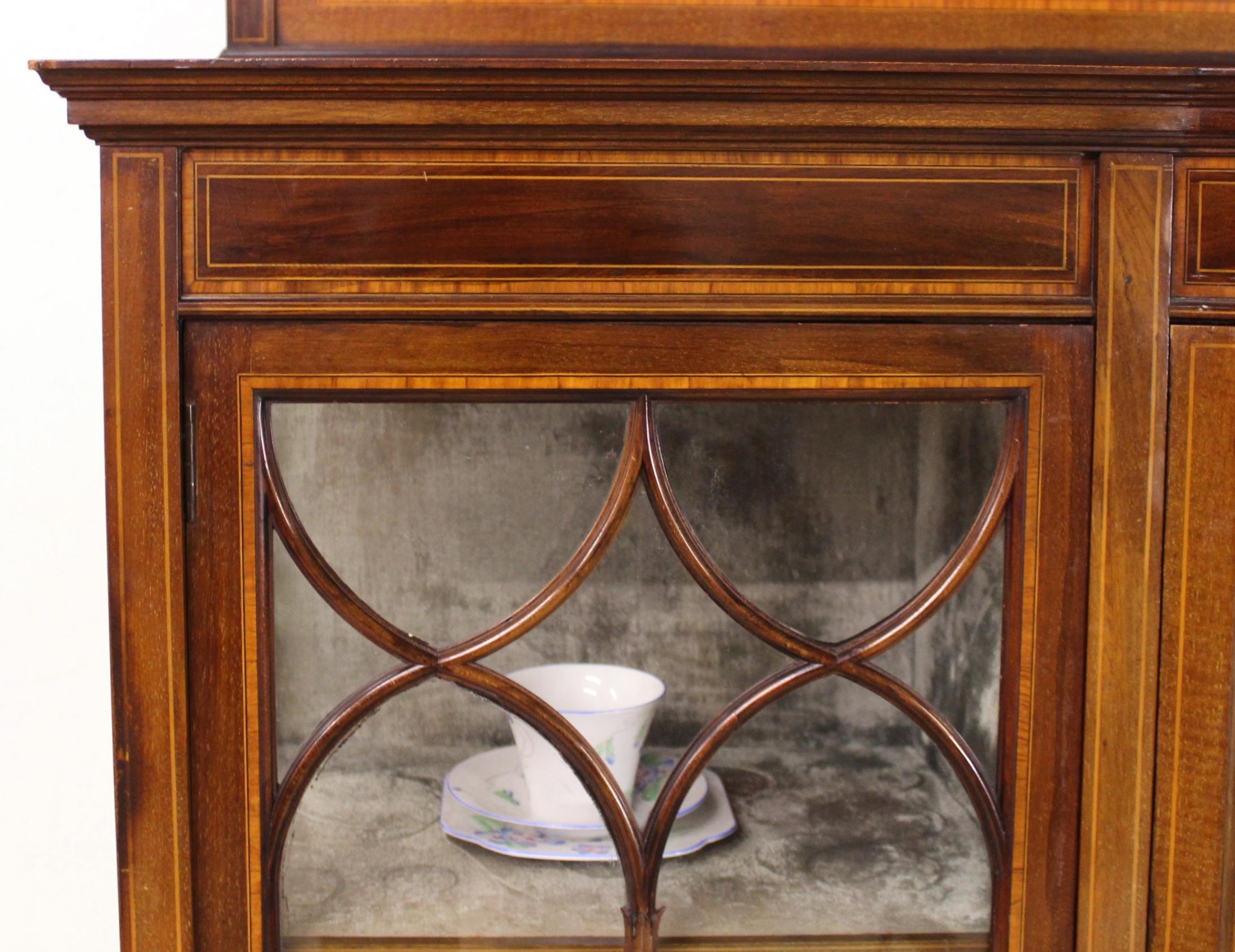 A stunning inlaid mahogany display cabinet from the Edwardian period. Of fine construction in solid mahogany, decorated with satinwood banding, stringing and floral marquetry inlay. Configured with one central , bow-fronted, cupboard door flanked by