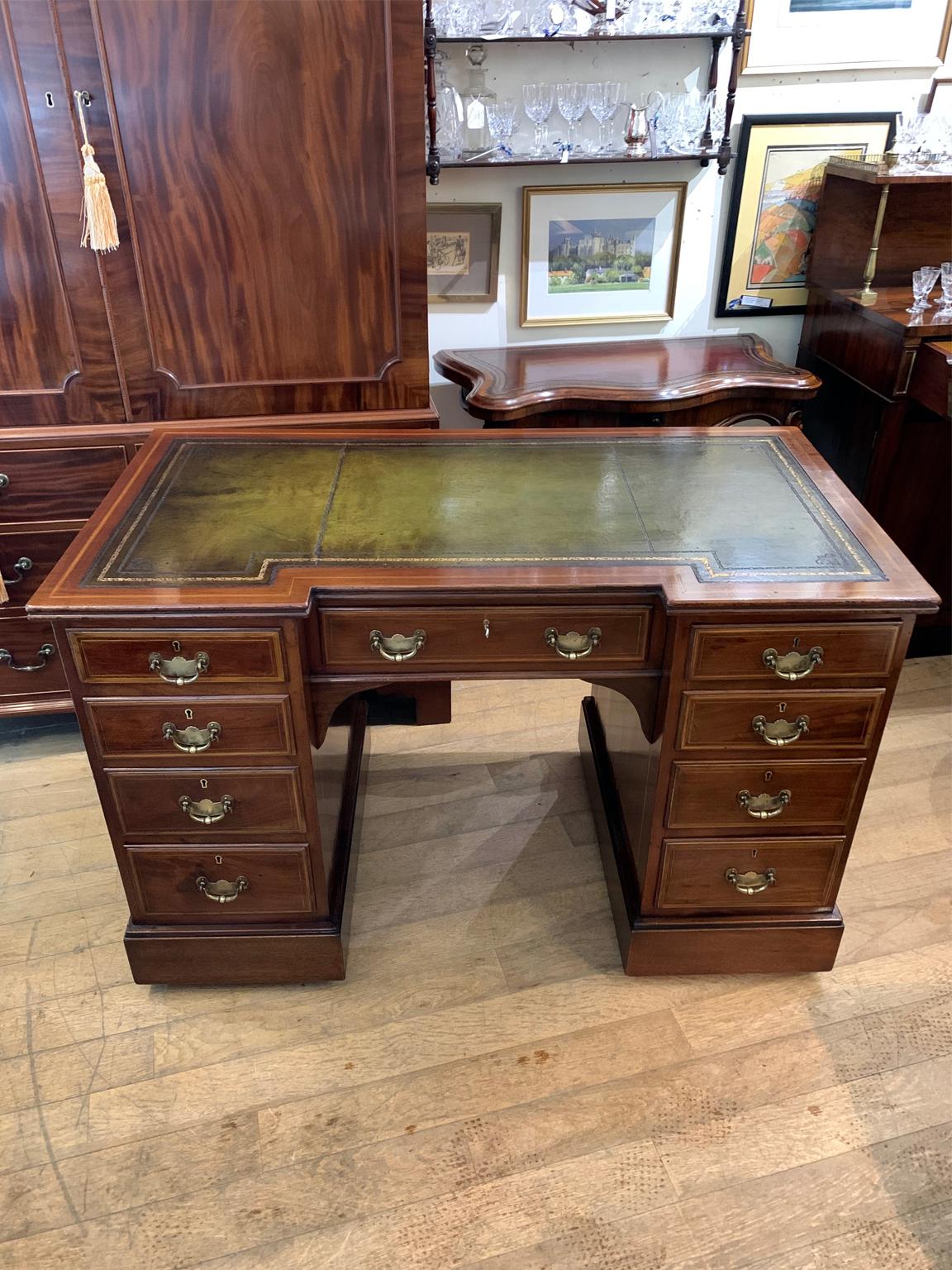 Edwardian inlaid mahogany knee hole pedestal desk with a leathered writing surface and nine drawers, all with fitted brass handles and lined oak drawers with working key.