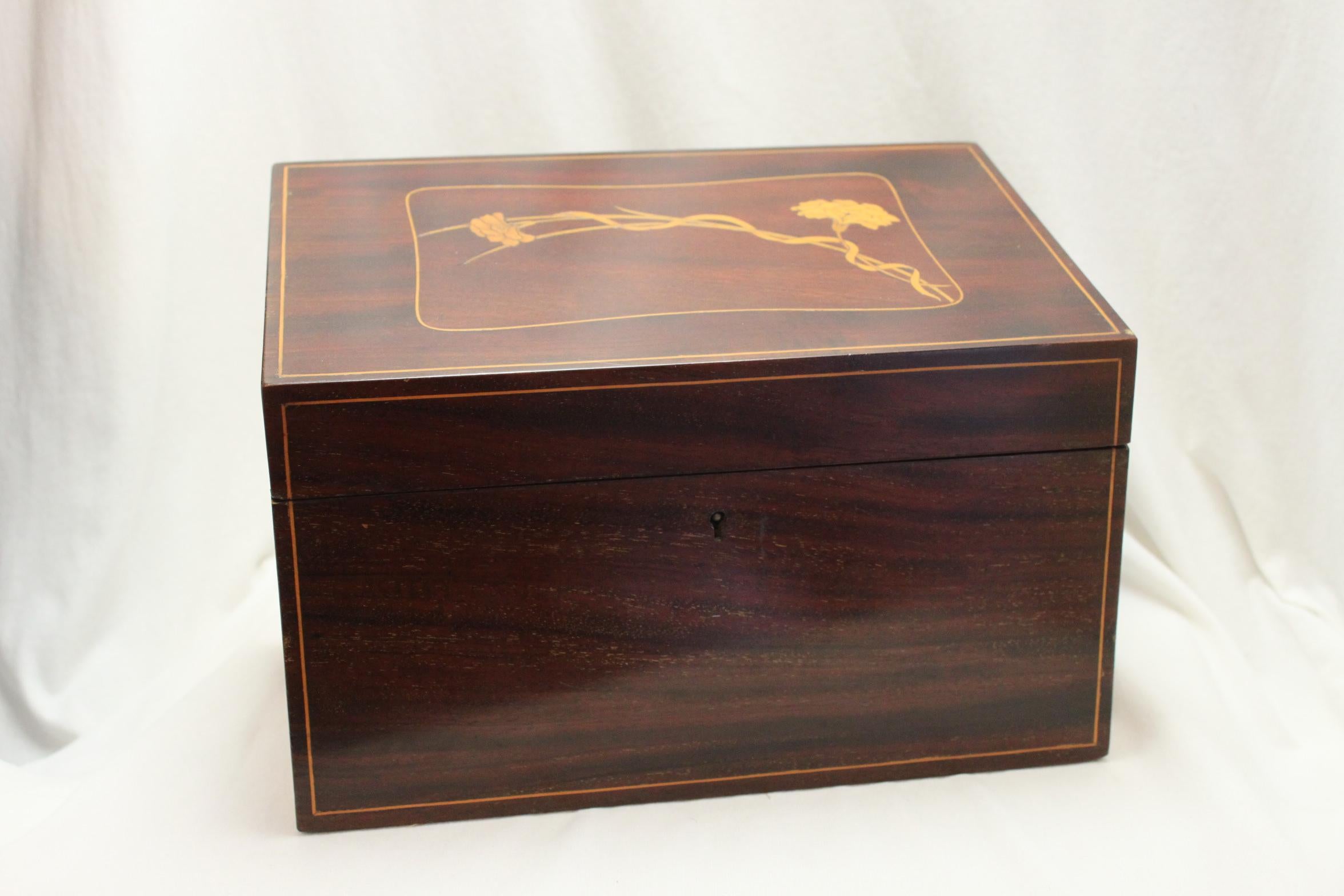 This very pretty Edwardian inlaid mahogany ladies stationery box would grace any ladies desk. The sloping lid is inlaid with a cushion shaped cartouche which contains a simple Art Nouveau rendition of two intertwined carnations. The interior is