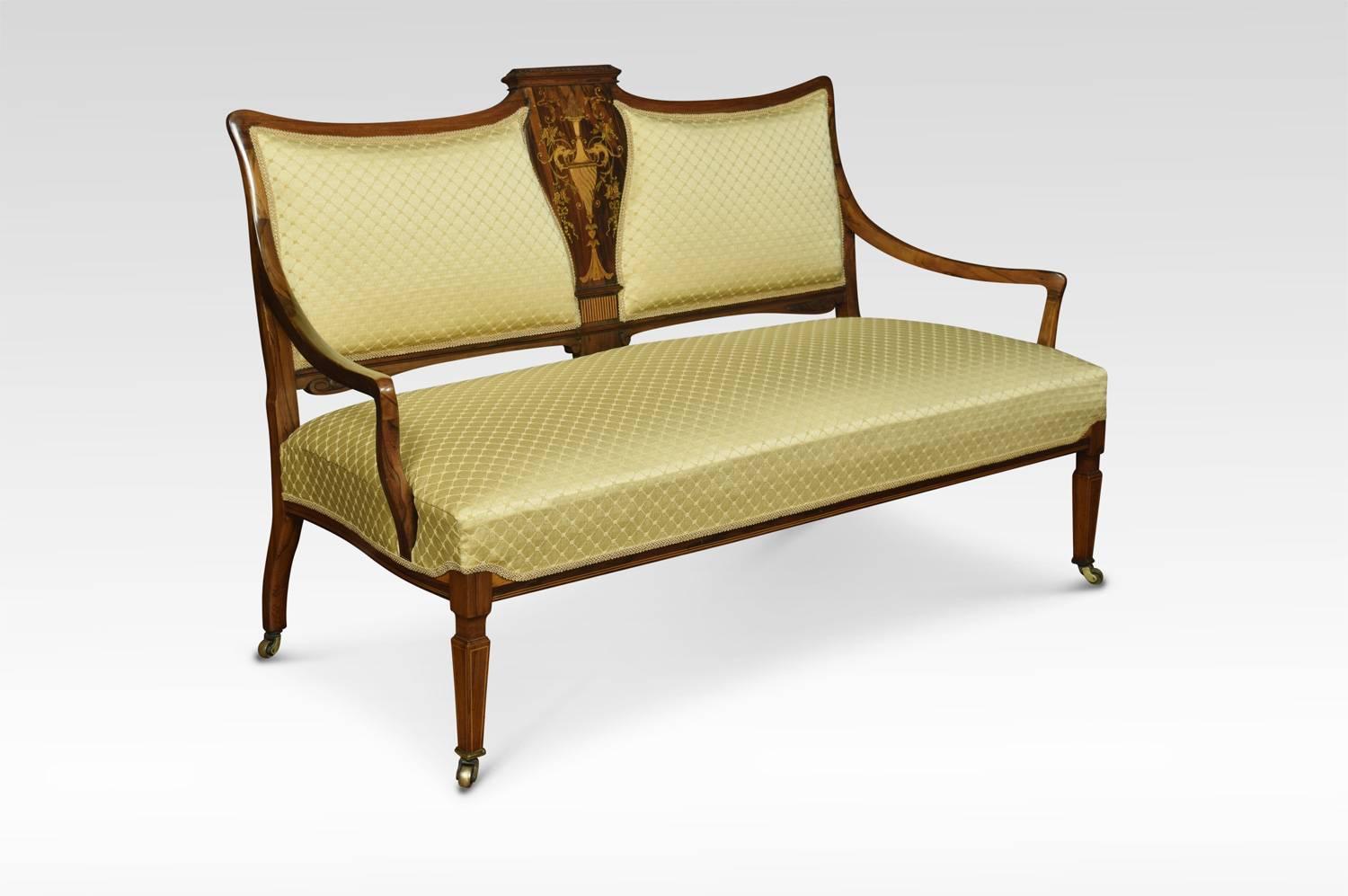 Edwardian inlaid rosewood two-seat settee. The shield shaped back with vase, and scrolling floral inlays with mother-of-pearl detail. The recently upholstered back and seat enclosed by out swept arms. All raised up on square tapering front legs with