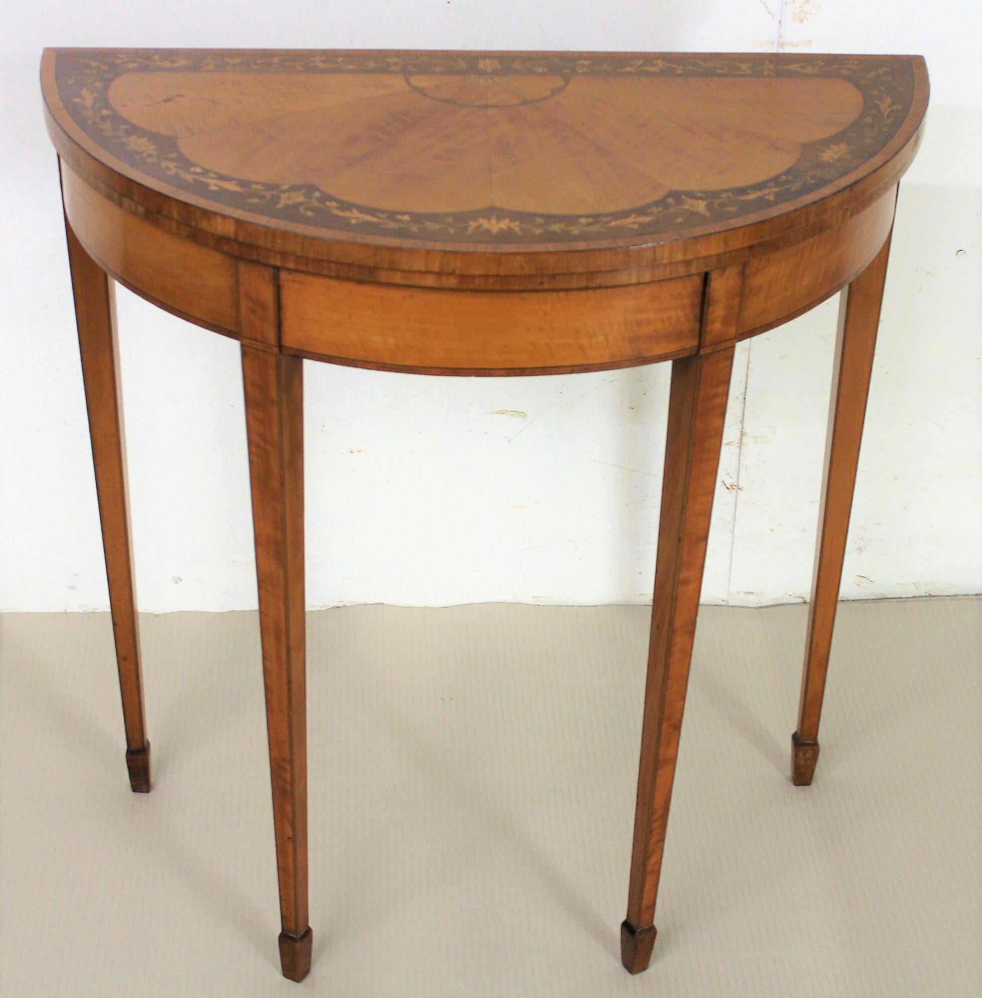 A charming Edwardian period demilune, or half moon, satinwood card table. Of Fine construction in satinwood and with attractive satinwood veneers onto a mahogany carcas. The half moon top is decorated with tulip wood banding, a walnut veneer border
