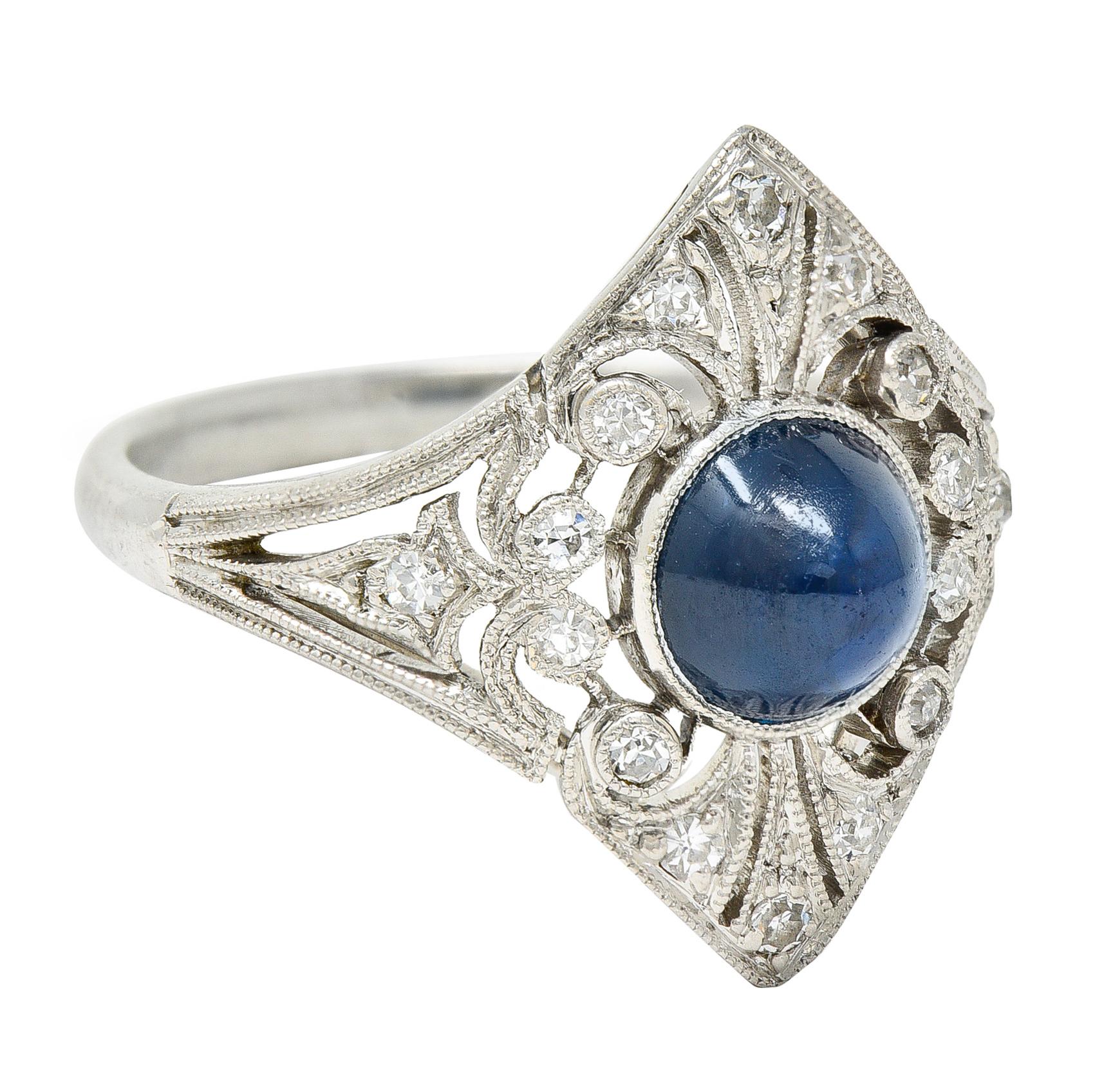 Dinner ring is navette shaped with milgrain detailing and decoratively pierced surface. Centering a bullet cabochon sapphire weighing approximately 1.60 carats. Medium dark and very slightly greenish blue in color - eye clean. Surrounded by single