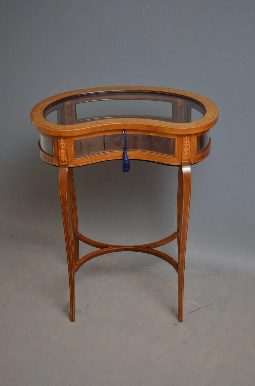 Sn4365, a stunning, Edwardian, kidney shaped, display table in mahogany, having hinged top with neoclassical marquetry fitted with original working lock and a key, and glazed sides flanked by finely inlaid panels, raised on tapering, outswept legs