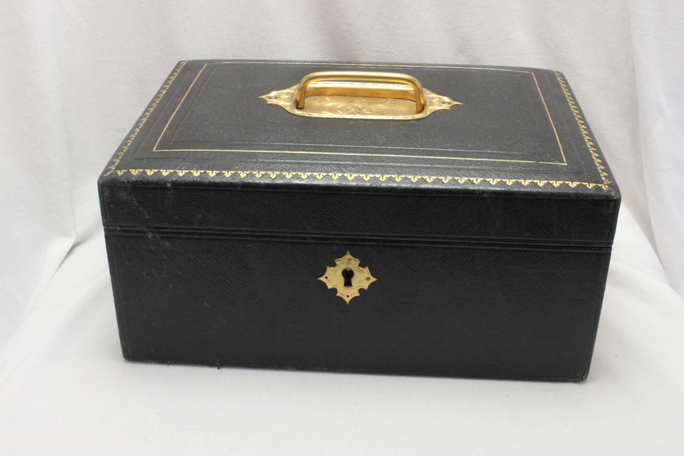 This attractive Edwardian ladies leather covered jewellery case is covered in black leather which is enhanced with gold tooling, a gilt escutcheon and a gilt carrying handle. The interior is covered with dark blue velvet and gilded black leather.