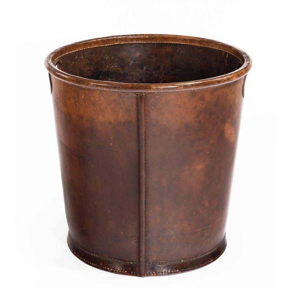 An Edwardian leather paper bucket with double stitching to the rim, base and inset 
carrying handles.