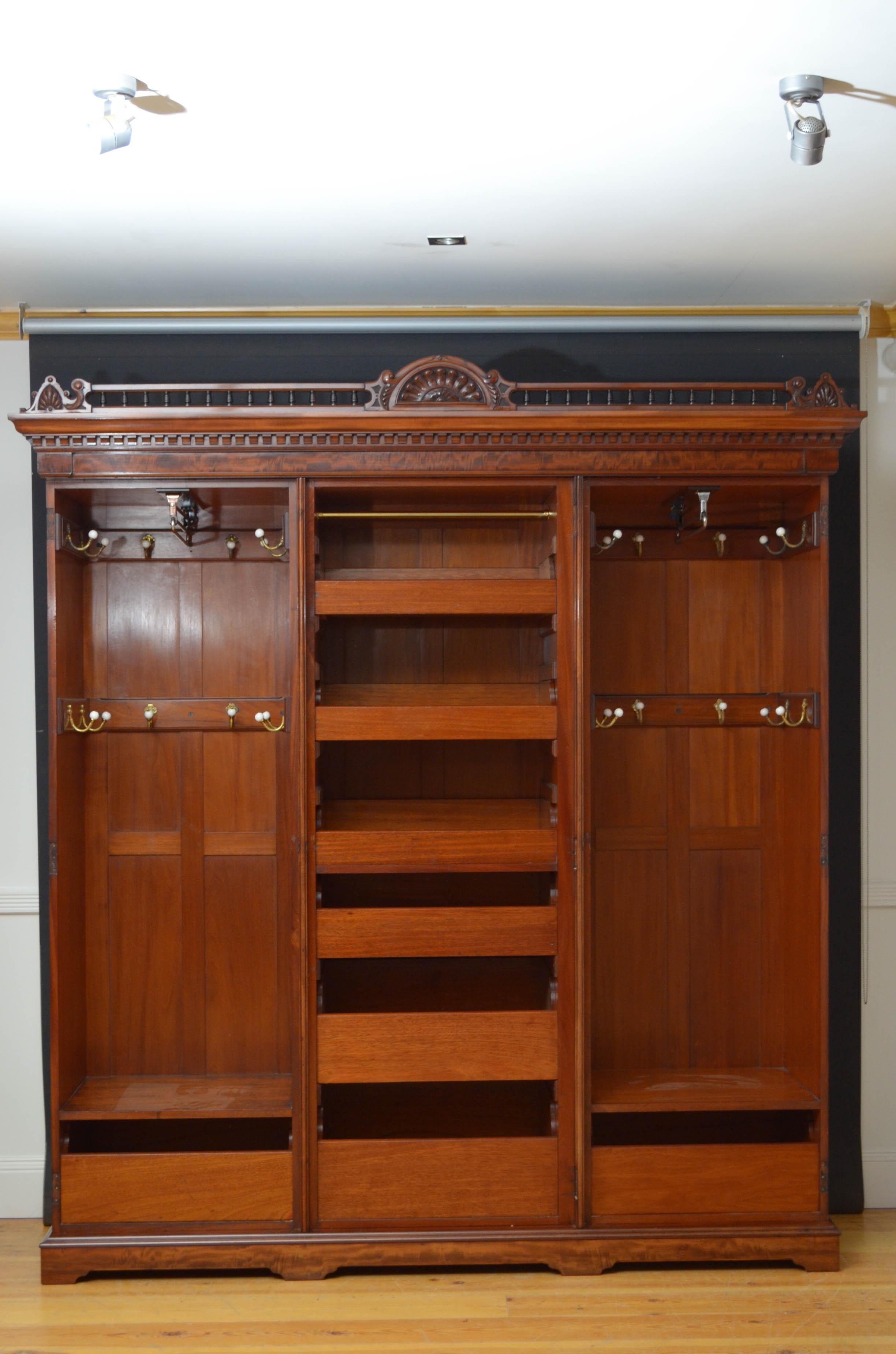 Sn4736, exceptional quality Edwardian wardrobe in mahogany, the cornice having carved centre flanked by spindles and shell carved corners over dentil decoration, all above mirrored centre door retaining original bevelled edge mirror and enclosing