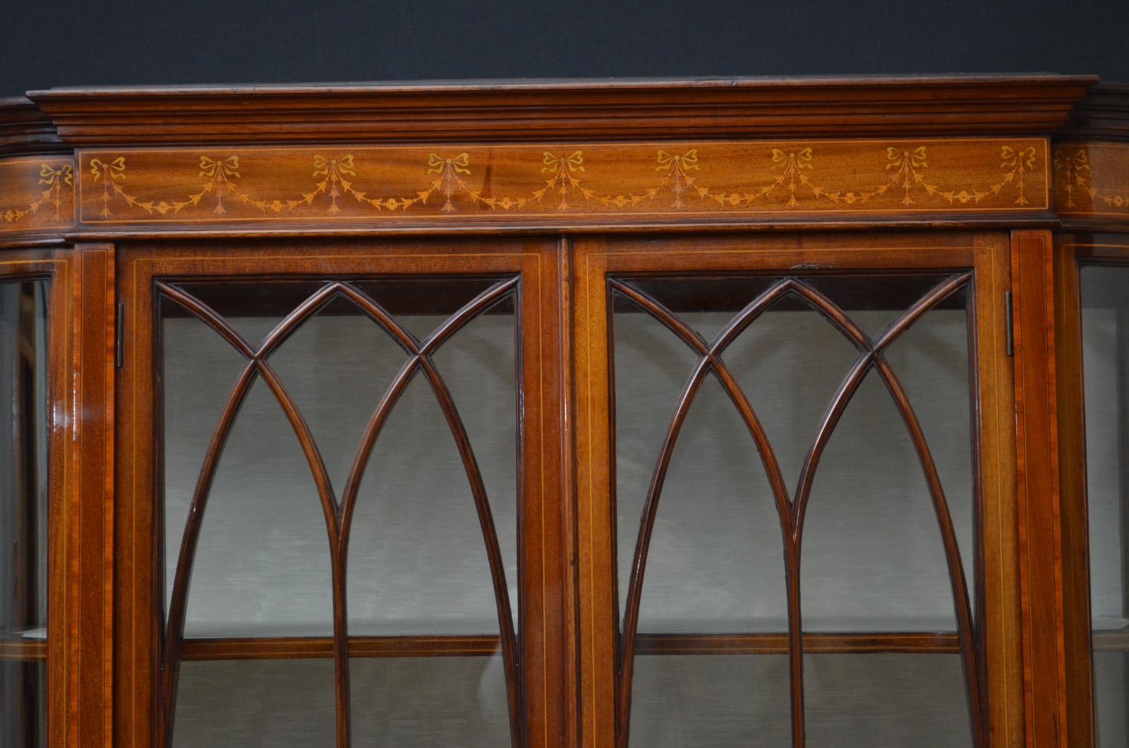 Sn4434, exceptional, mahogany display cabinet, having moulded cornice with harebells and swags inlaid frieze, a pair of glazed doors fitted with original brass handles and enclosing lined interior with 2 shelves, flanked by bowed ends and further