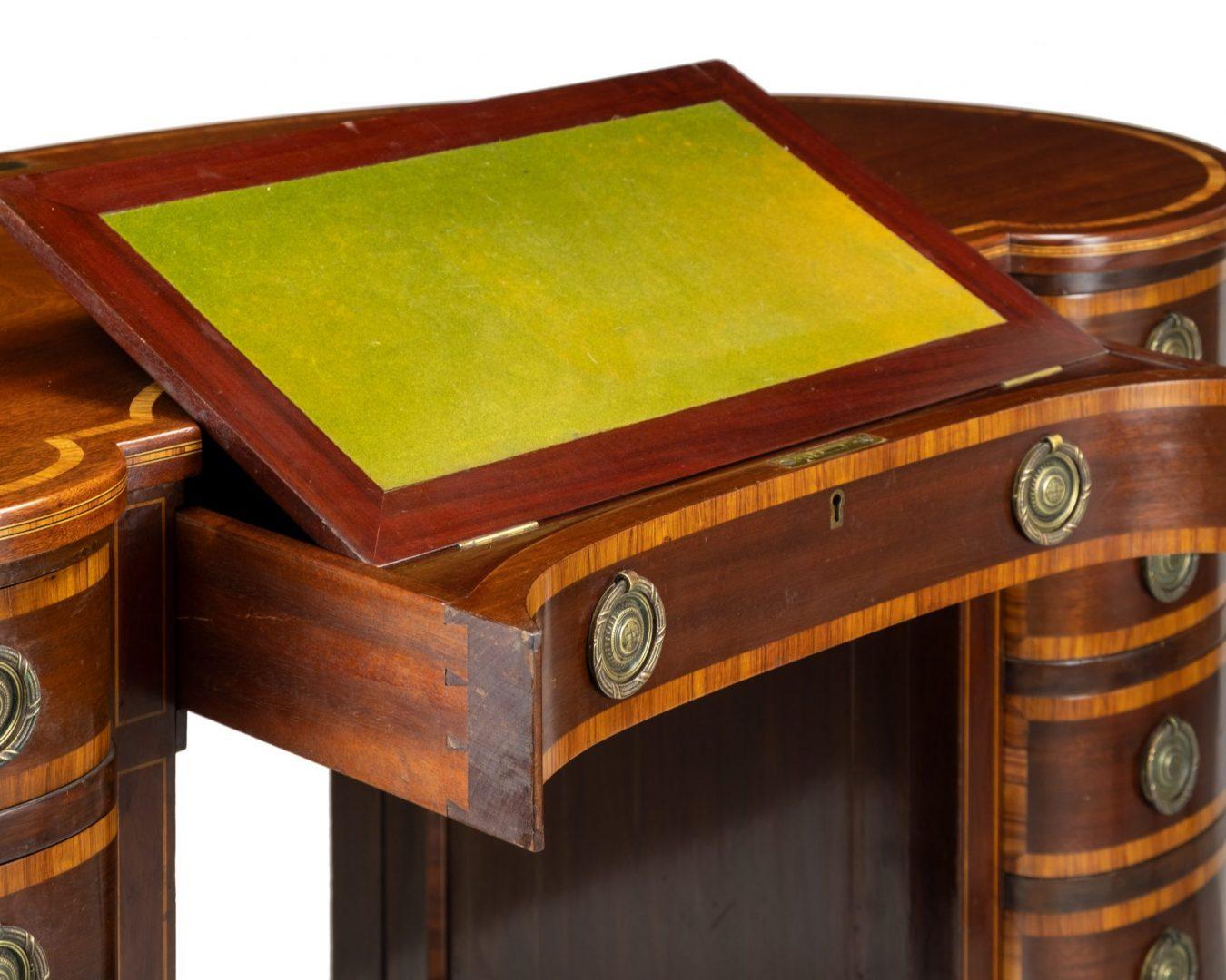 Edwardian mahogany and satinwood cross-banded kidney shaped writing desk.
The shaped top above an arrangement of eleven drawers with circular brass ring handles and low square tapering supports with brass caps and casters, bearing a presentation