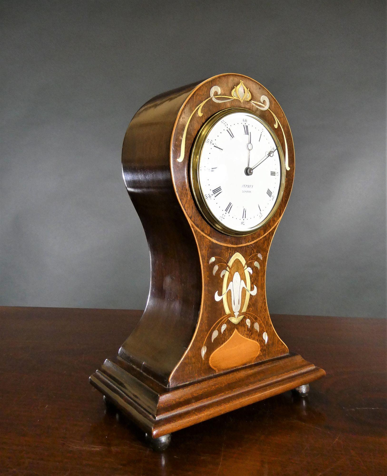 Edwardian Mahogany Balloon Mantel Clock, Asprey, London
 
Edwardian mantel clock housed in a balloon shaped mahogany case with satinwood line stringing and beautifully inlaid with mother of pearl, satinwood, brass and pewter with brass bezel and