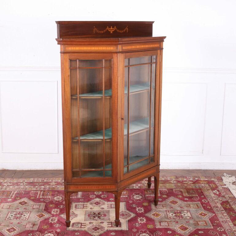 English Edwardian Bookcase in Mahogany.  In the centre is a lovely single door with the original glassed glass, opening to upholstered shelves, all supported by square tapered legs and spade feet. C.1910