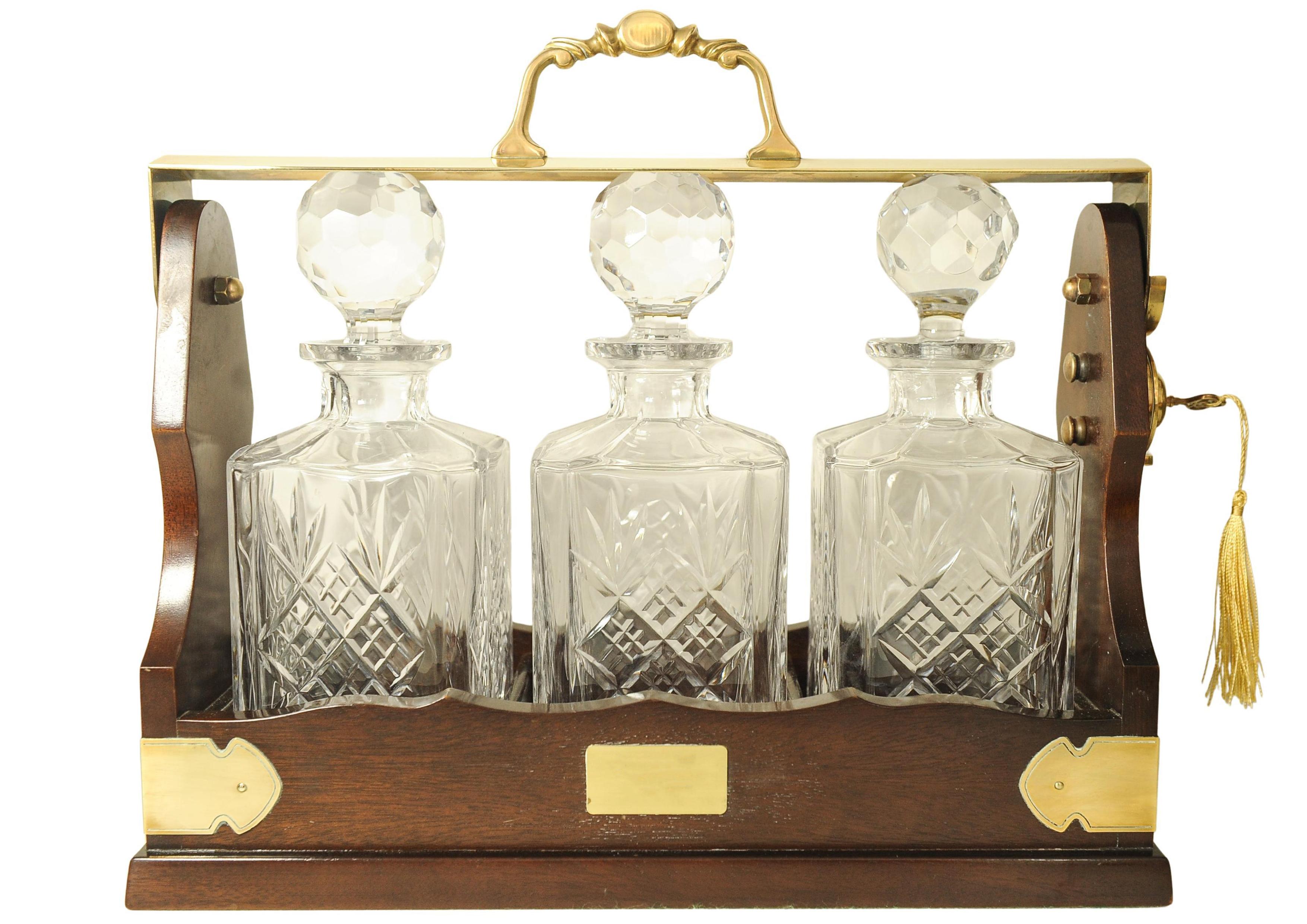 Tántalo eduardiano de caoba y latón con juego de tres decantadores cuadrados de cristal Británico en venta
