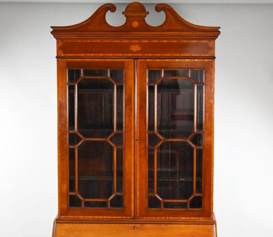 For sale is a good quality Edwardian mahogany bureau bookcase, originally retailed by Harrods. The bookcase has a swan neck pediment to the top, over two glazed doors with a fall front below, opening to reveal a fitted interior. The bureau base has