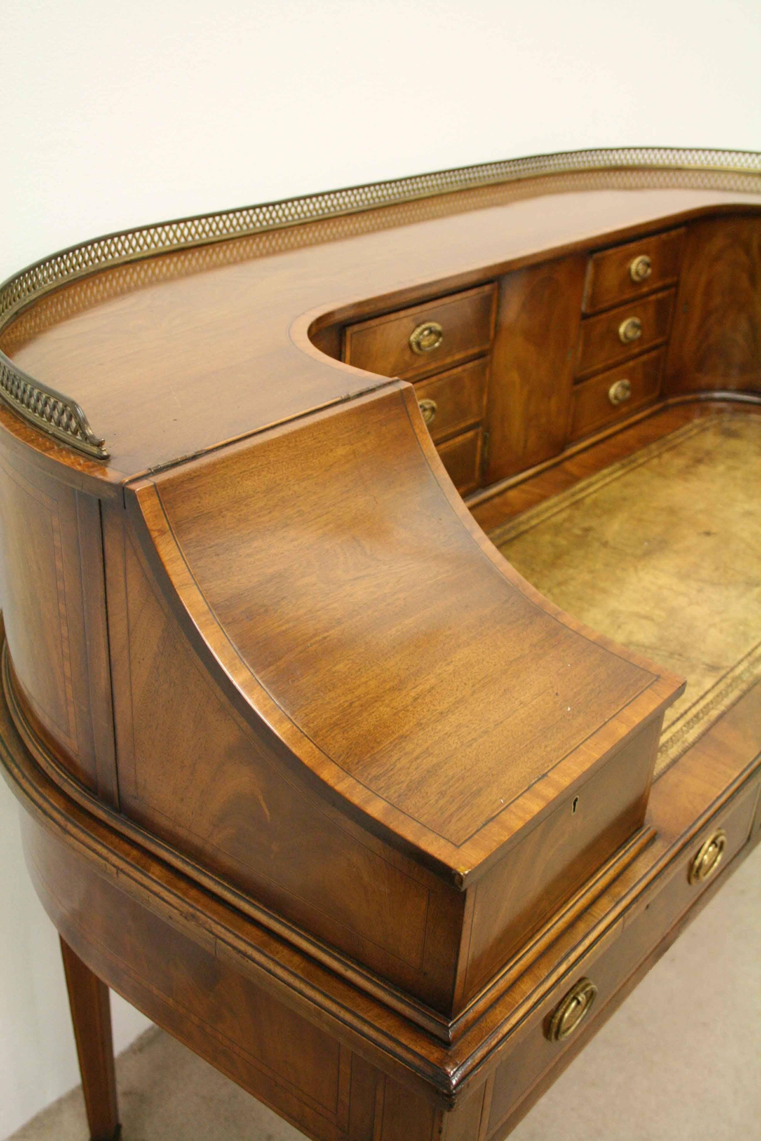 Edwardian finely figured mahogany Carlton house desk with satinwood, boxwood and ebony inlay, circa 1900. The top with fretted brass gallery above the typical back with various drawers with gilded brass handles and cupboards. Below the writing