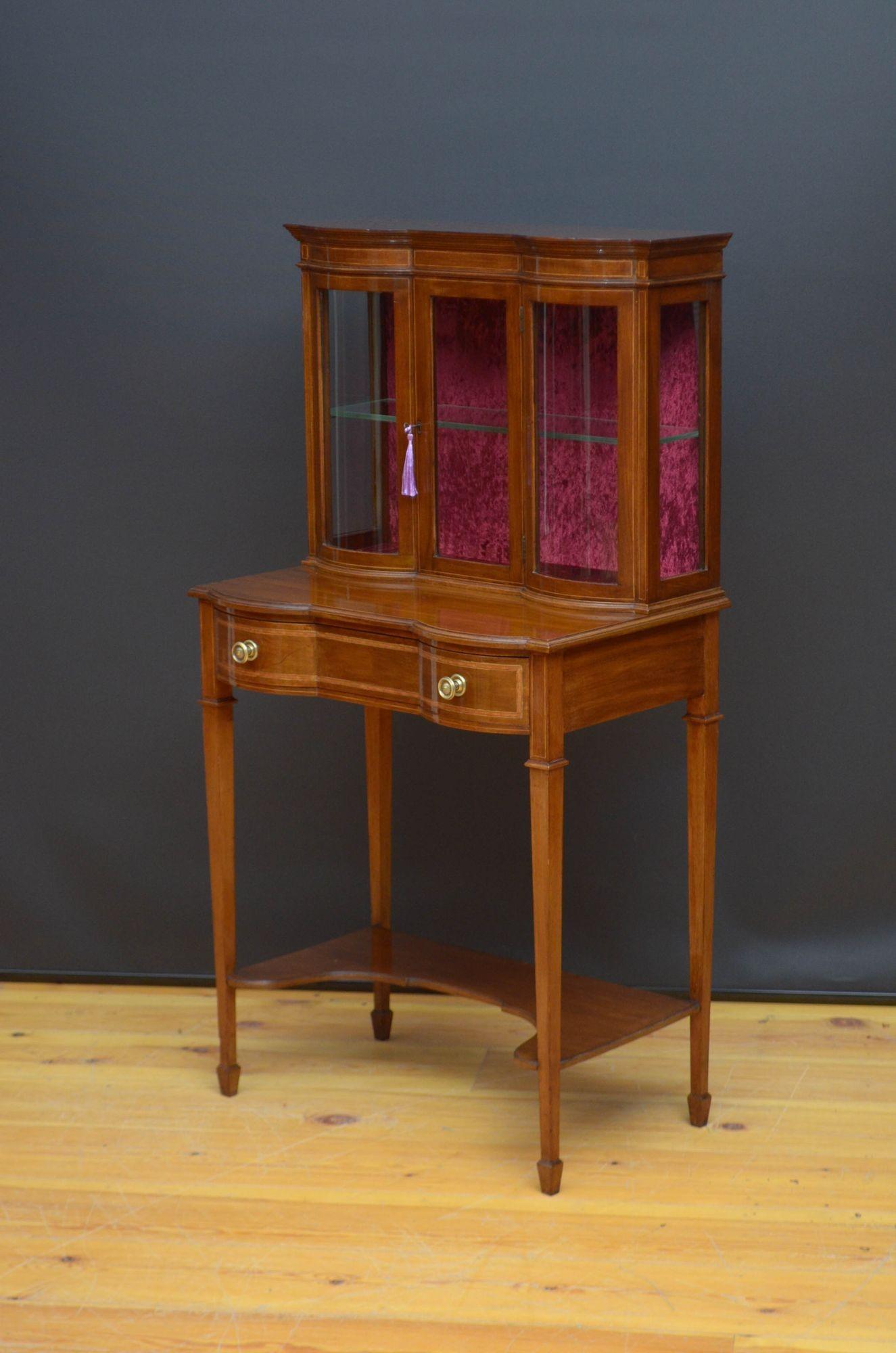 R039 Edwardian mahogany, serpentine display cabinet of unusually narrow proportions, having polished top with moulded edge above satinwood crossbanded frieze and glazed door fitted with original working lock and key and enclosing newly relined