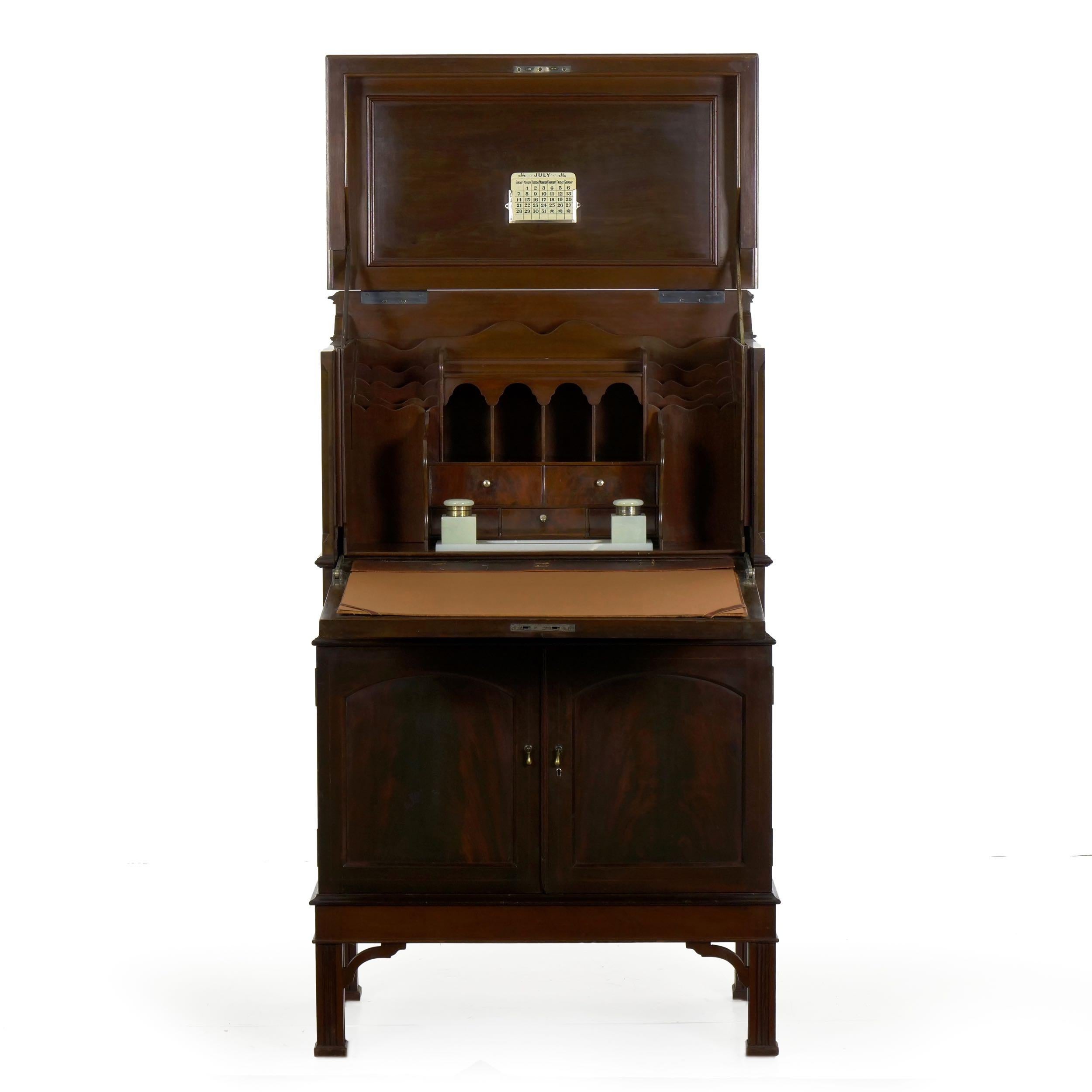 With a smooth operating action, this remarkably high quality English Edwardian period mahogany writing desk features a built-in Chubbs safe in the lower cabinet. The top and fall front act together using a hinged action, allowing the desk to open