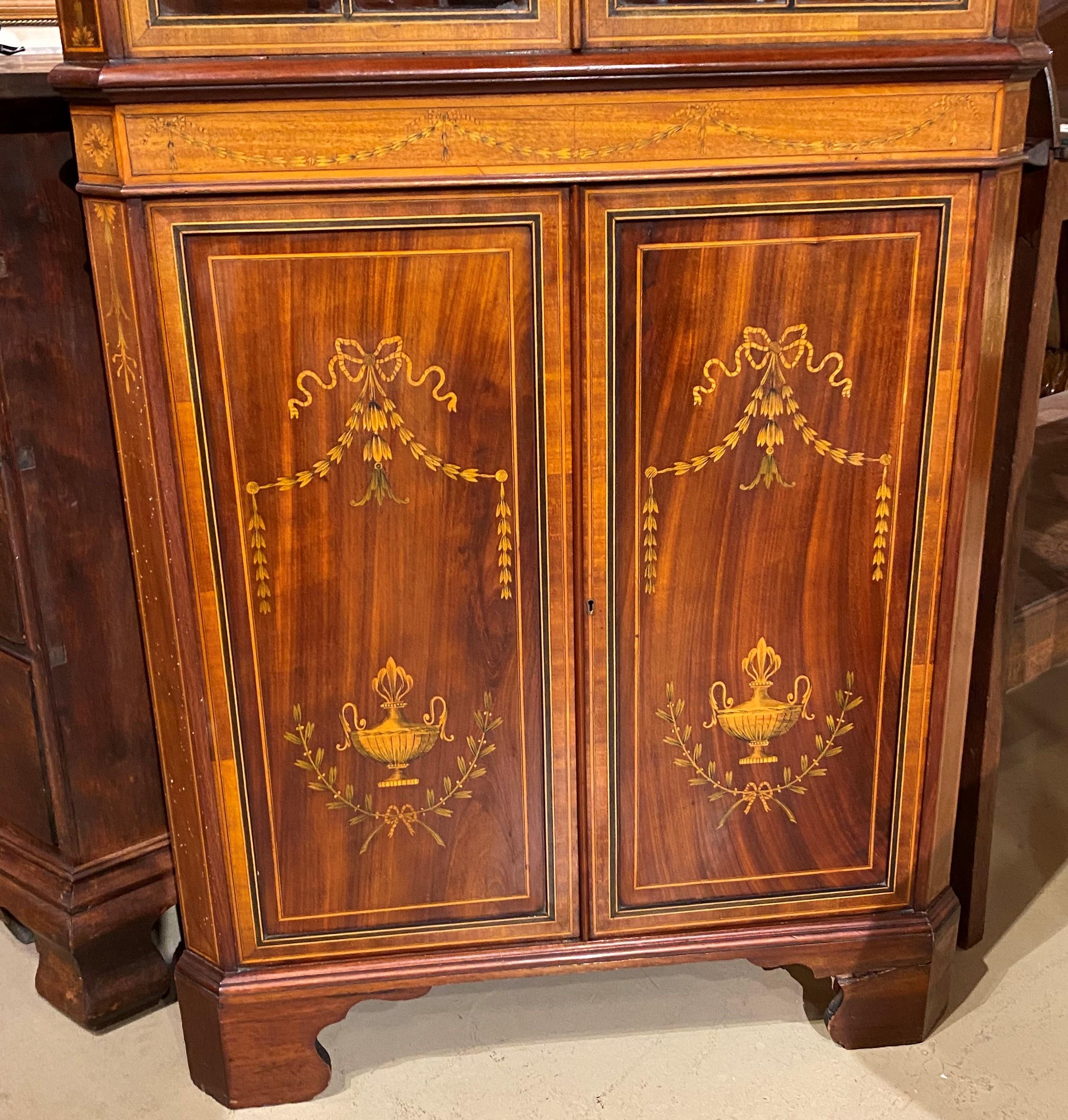 A beautiful example of an Edwardian period mahogany glazed door one-piece corner cupboard with molded checkered cornice surmounting a case with two glass doors with line border inlay, opening to three interior shelves, flanked by canted corners,