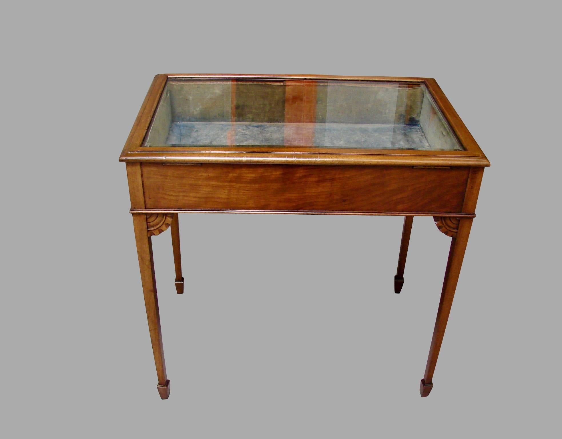 An Edwardian table vitrine with an inset bevelled glass hinged locking top opening to the velvet lined display bay, resting on square tapered legs ending in spade feet, the corners braced by carved brackets, circa 1910. Complete with key.
 