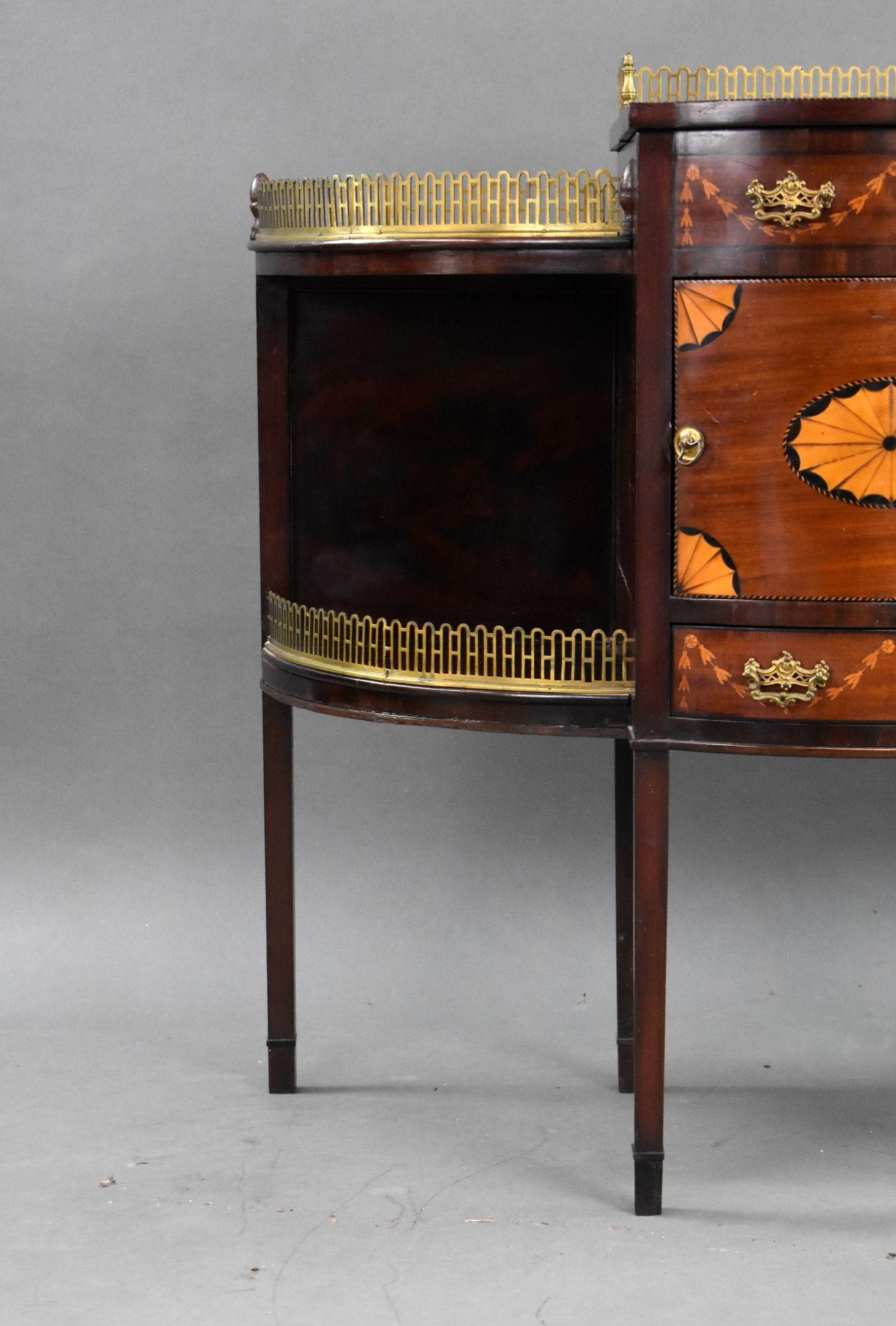 For sale is a good quality Edwardian mahogany inlaid sideboard, having a brass gallery surrounding the banded edge, above a single inlaid and bow fronted faux drawer with a cupboard below, flanked by shelves, raised on tapered legs terminating on