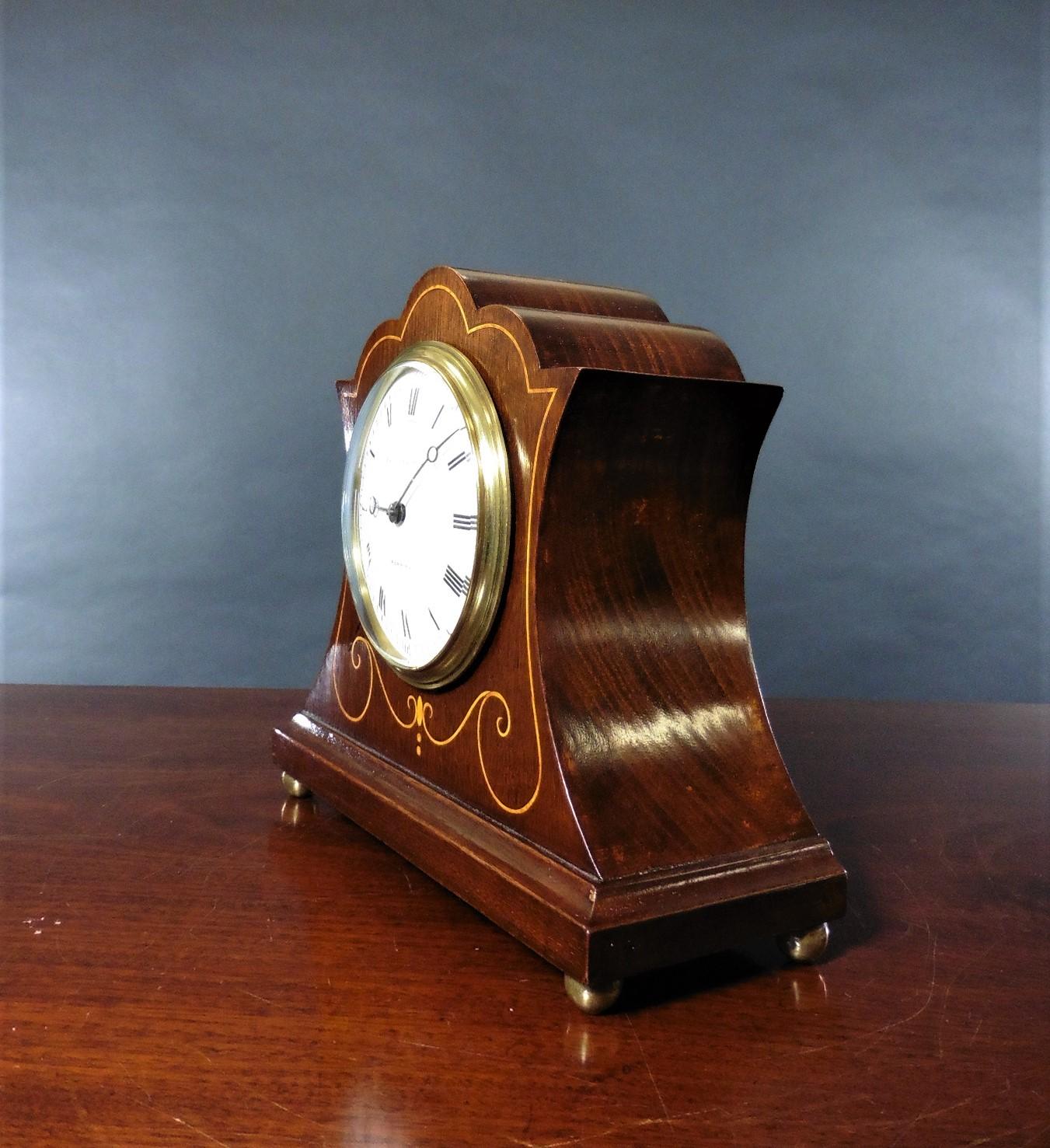 Edwardian mahogany mantel clock standing on a raised stepped plinth and resting on four brass ball feet with satinwood line inlay.

Enamel dial with Roman numerals and original ‘blued’ steel hands signed Botley and Lewis, Reading.

Eight day