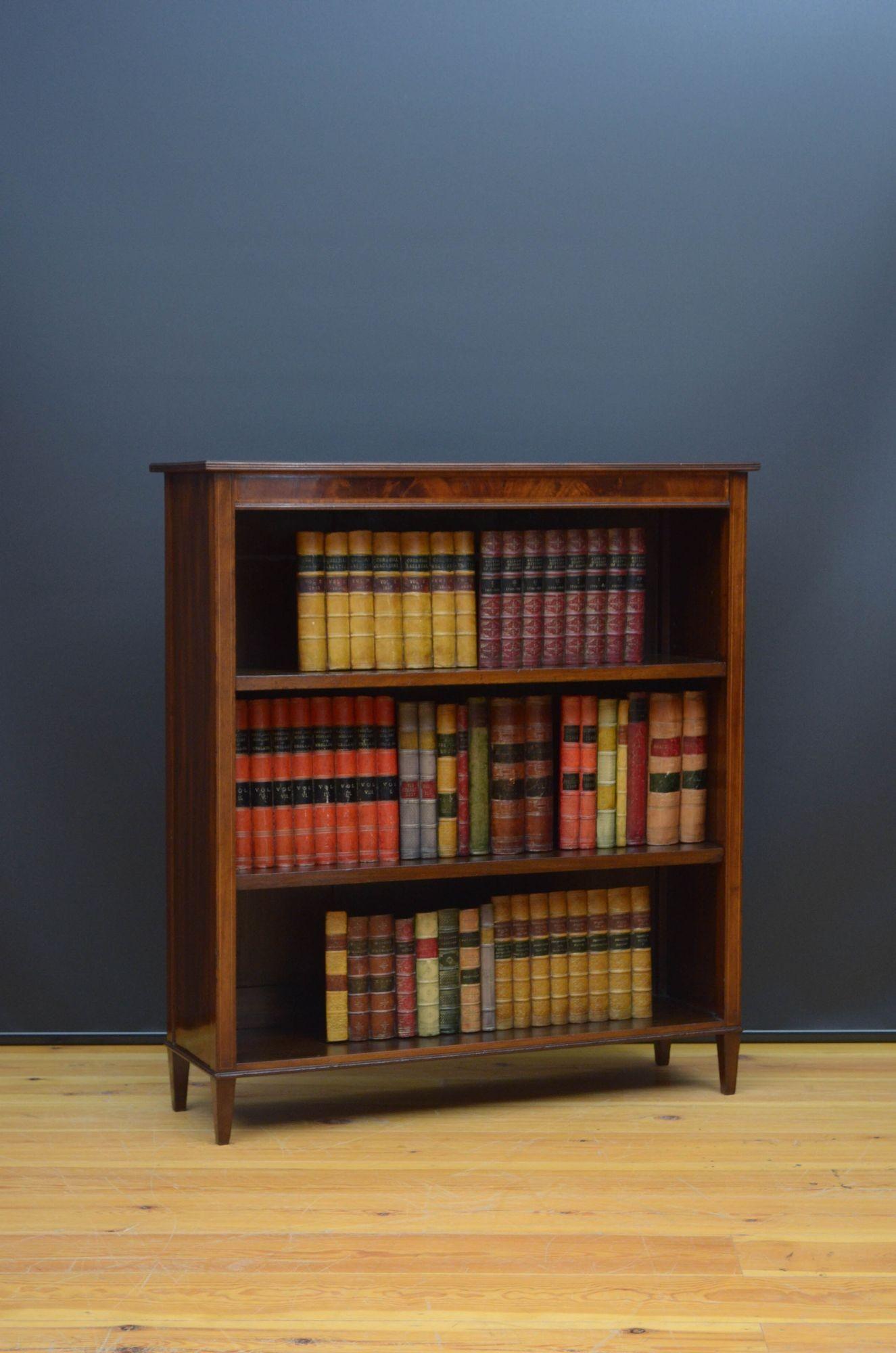 St017 Edwardian mahogany open bookcase, having figured mahogany top with satinwood crossbanded edge above flamed mahogany frieze and two height adjustable shelves, all flanked by inlaid pilasters terminating in tapered legs. This antique bookcase is