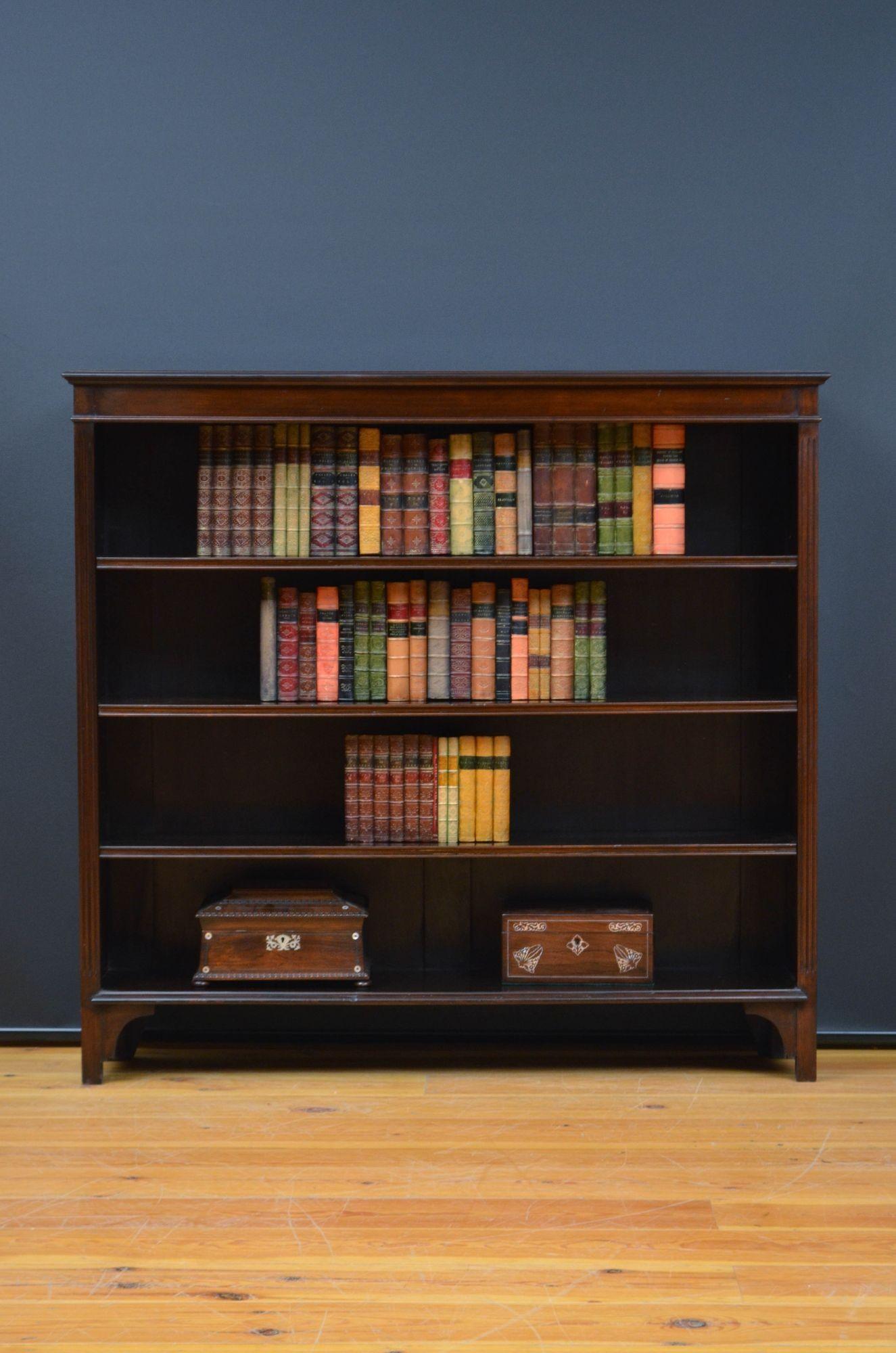 Sn5537 Edwardian mahogany open bookcase of rich, deep colour, having oversailing top with moulded edge above shallow frieze and three height adjustable shelves, all flanked by reeded pilasters, standing on shaped bracket feet. This antique bookcase