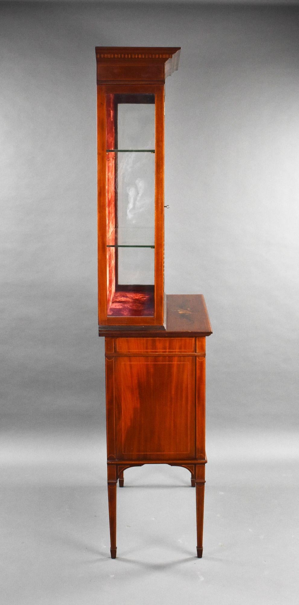 For sale is a good quality Edwardian mahogany and satinwood polychrome painted display cabinet, the upper section with glass shelves, enclosed by an astregal glazed door, the base with twin musical trophy painted doors on square tapered legs. This