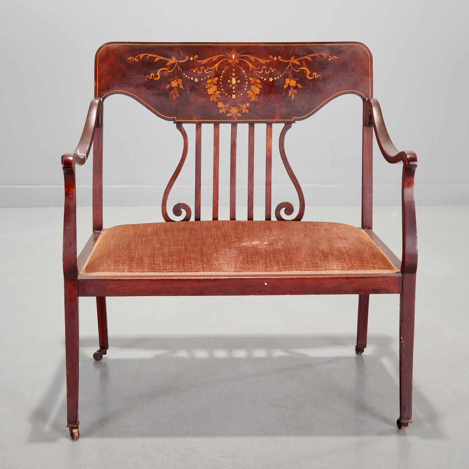 Early 20th c., settee with mother of pearl and satinwood inlay in a floral wreath and swag design set into a flame mahogany back. A lyre slat back lends a lightness to the piece. With a light brown strie velvet upholstered seat and contrasting