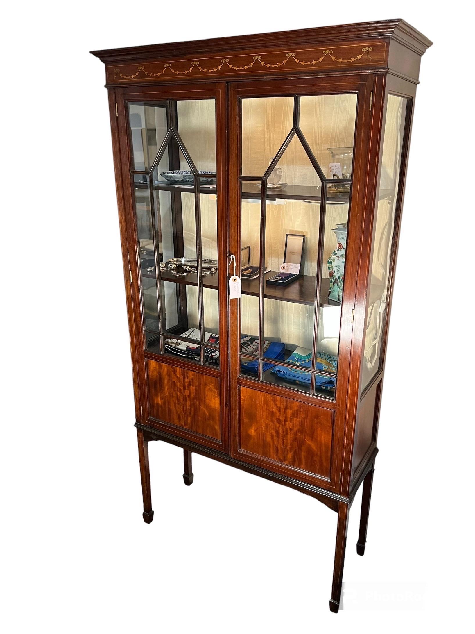 Edwardian Mahogany Cabinet with Inlaid panel at 
cresting over 2 glassed doors revealing 2 shelves,
over 2 panels concealing a lower shelf. With 1 key.