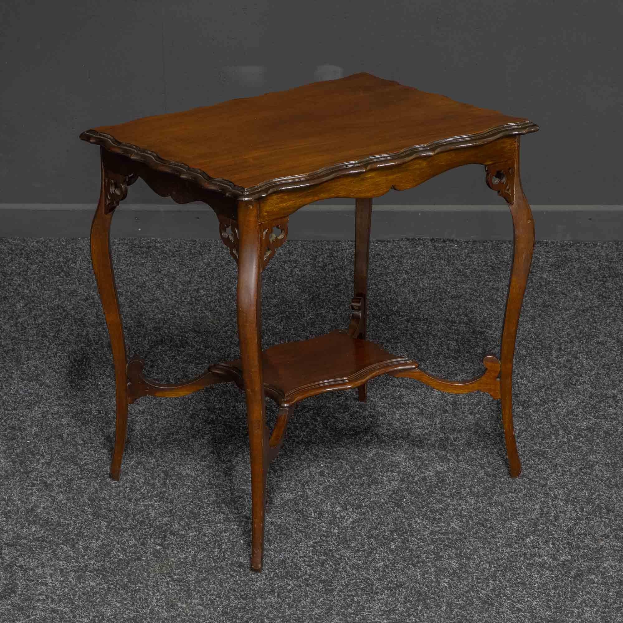 An attractive mahogany window table from the Edwardian period. The top is nicely figured and has an unusual 'wavy' edge. The cabriole legs have fretted brackets which adjoin the shaped apron. The under tier compliments the top in design and gives