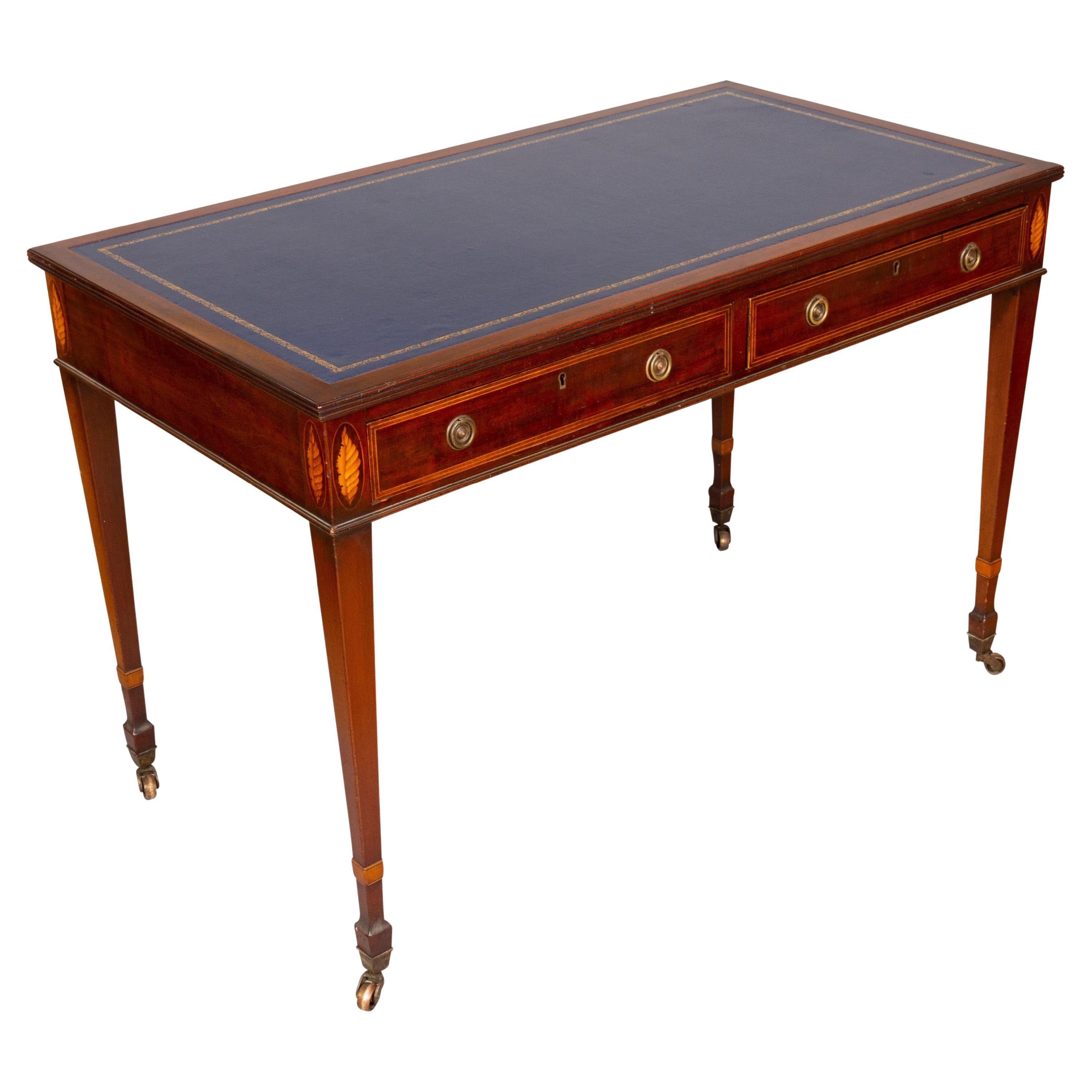With new tooled blue leather top set in a wood surround over two frieze drawers with shell inlays flanking, raised on square tapered legs and casters.
