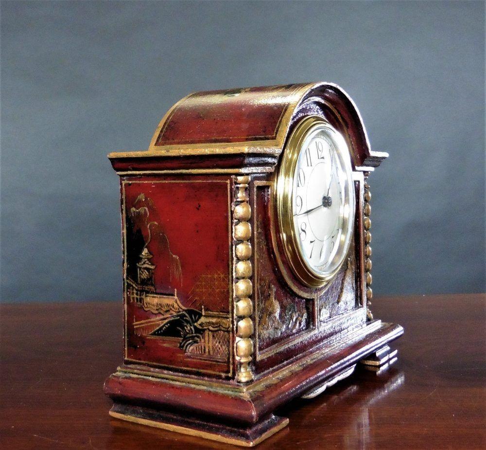 Edwardian mantel clock in a break arch case with raised chinoiserie decoration on a red ground, barley twist columns to either side of the case and resting on pad feet.
Brass bezel with convex glass, enamel dial with Arabic numerals and original
