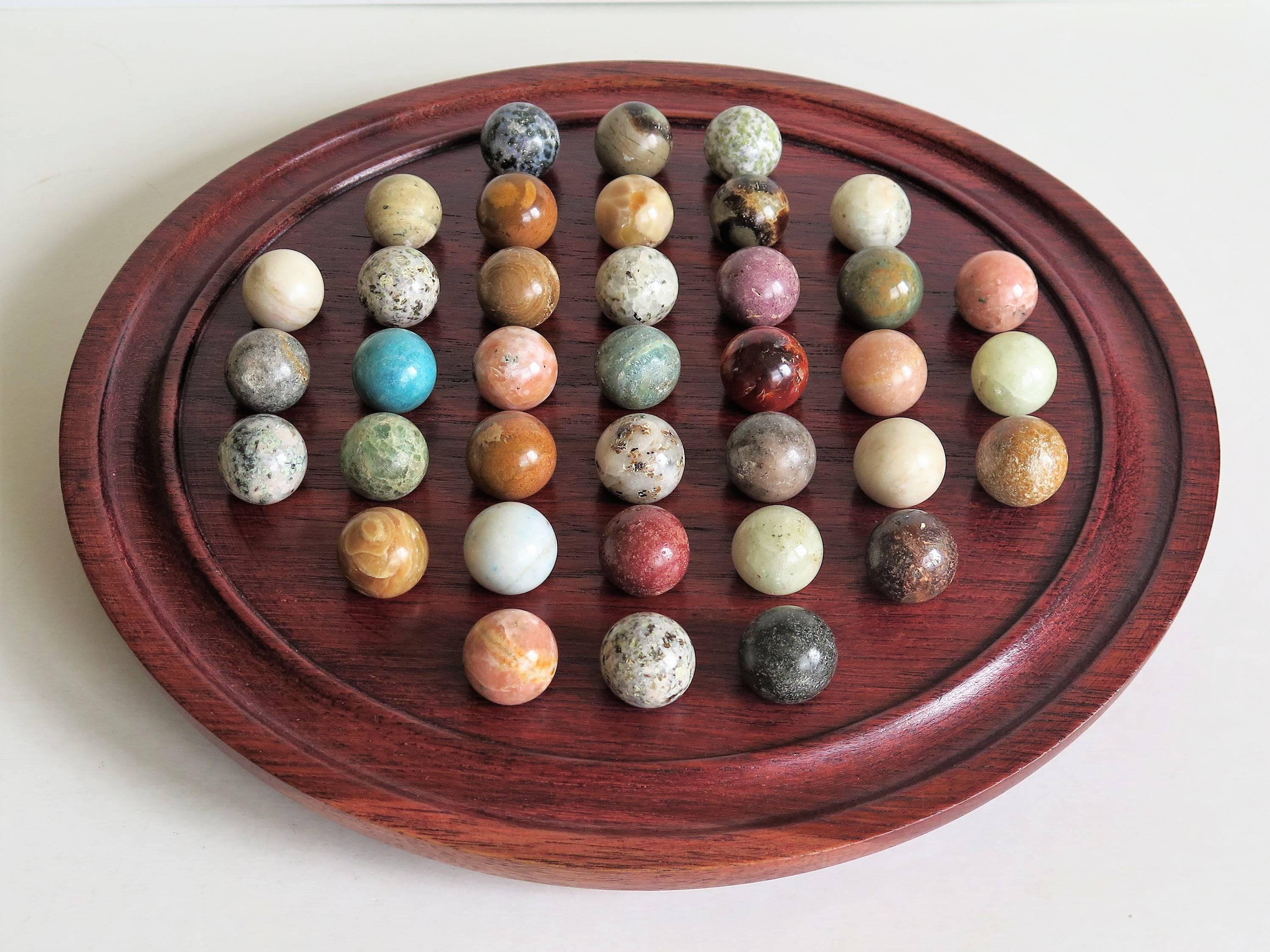 This is a complete Game of 37 hole marble solitaire with a hardwood board and 37 beautiful individual agate marbles, which we date to the early 20th century.

The circular turned board is made of Hardwood with a gallery to the outer rim. There are