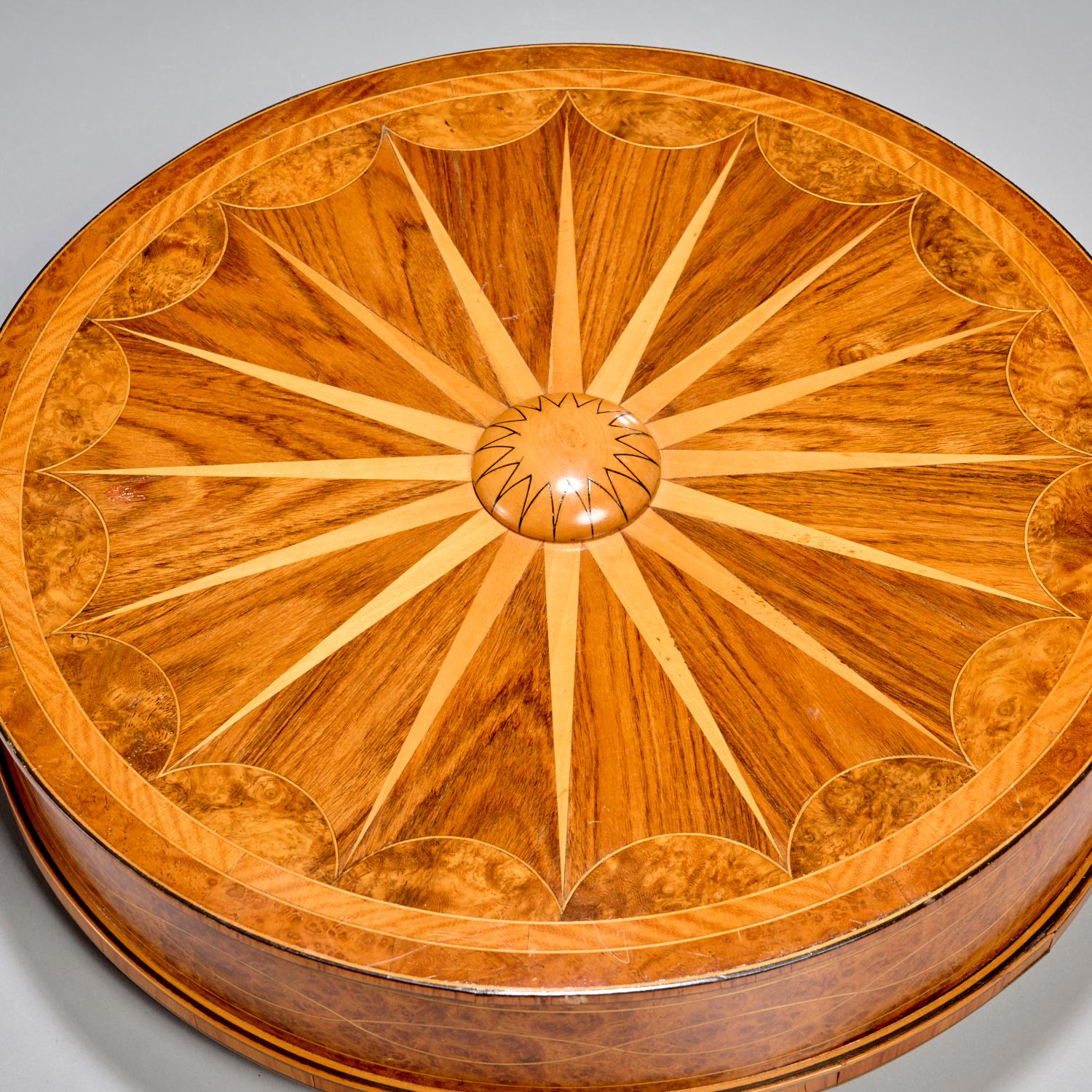 Edwardian Marquetry Sunburst Walnut and Burlwood Box, England, Late 19th Century

A finely crafted Edwardian circular parquetry box, England, late 19th century. The lid is adorned with an intricate sunburst marquetry pattern radiating from a carved
