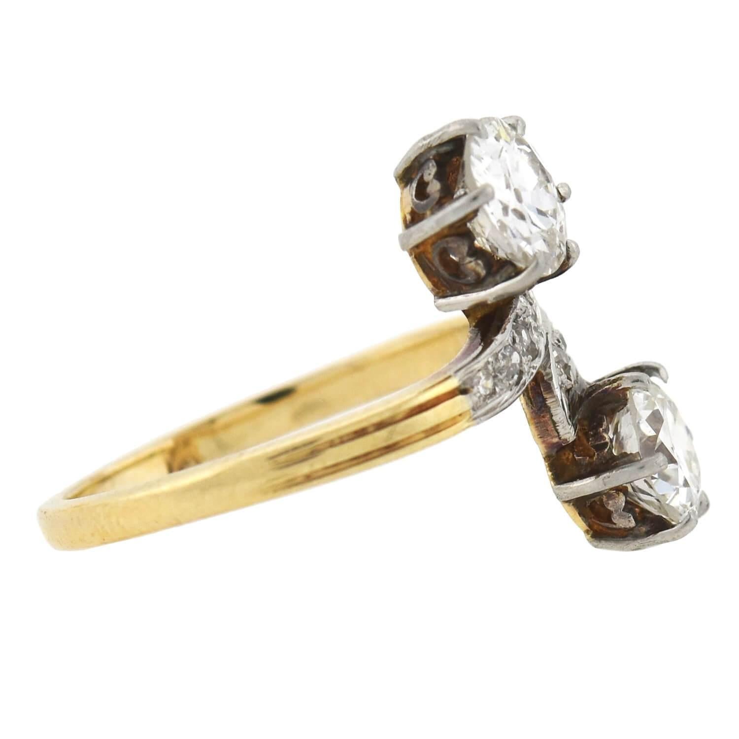 A unique and exquisite diamond bypass ring from the Edwardian (ca1910) era! Crafted in 18kt yellow gold topped with platinum, this piece features two old Mine Cut diamonds nestled together at the center, forming a stylish 