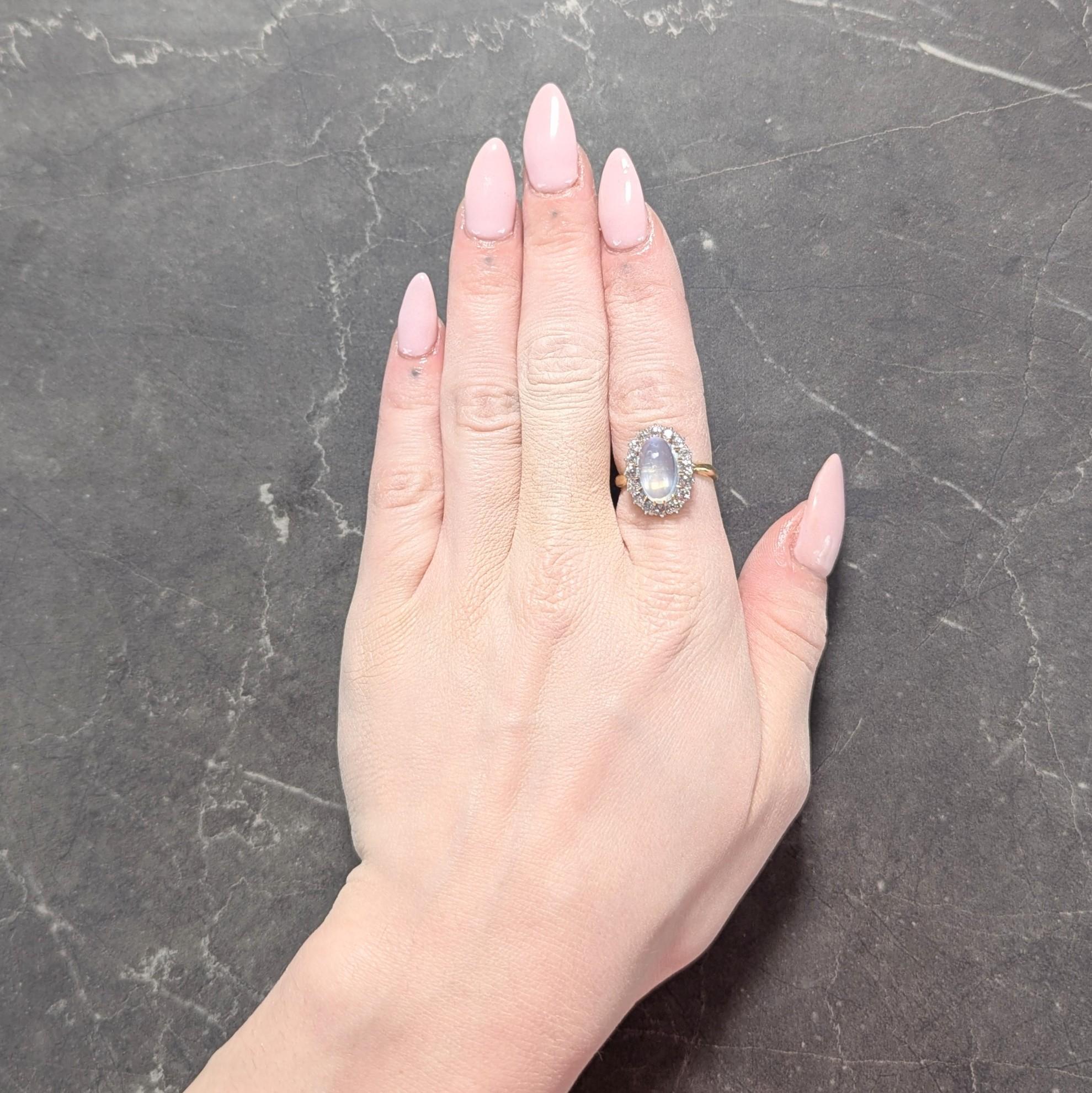 Centering an oval-shaped moonstone cabochon measuring 7.0 x 12.0 mm
Translucent colorless body displaying vivid blue adularescence
Set by talon prongs with platinum-topped halo surround
Comprised of old European cut diamonds
Weighing approximately