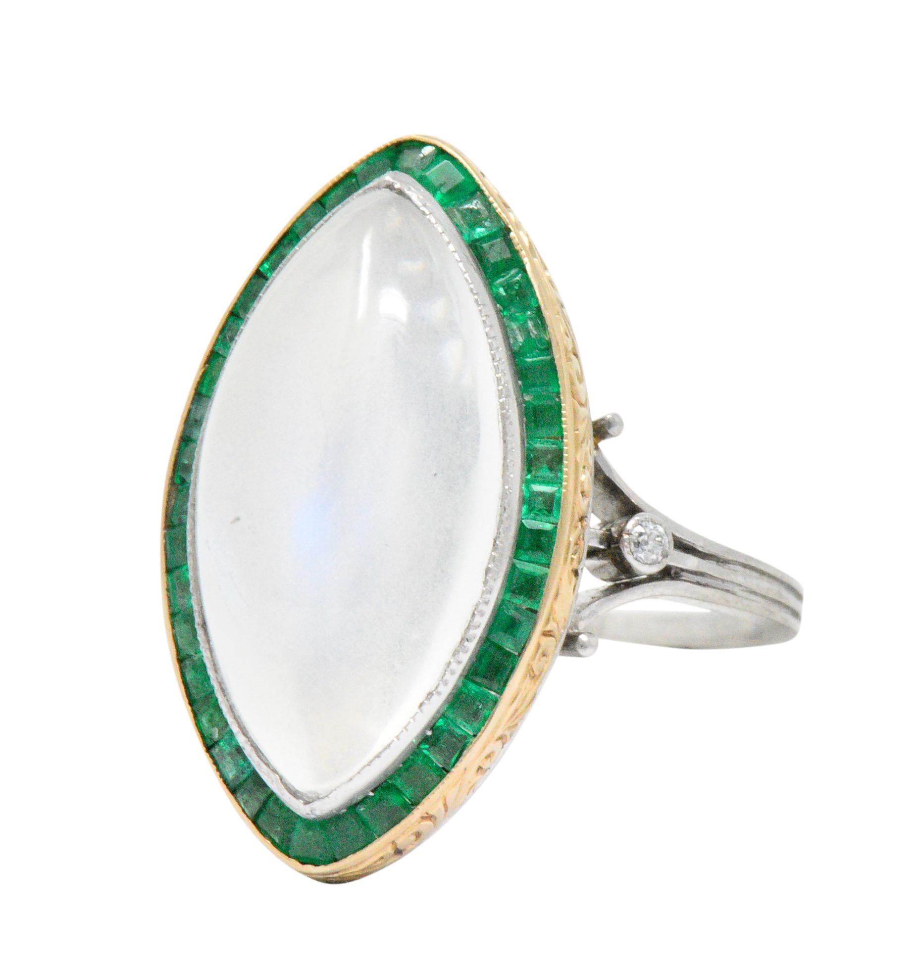 Substantial navette shaped ring centering a moonstone cabochon measuring approximately 20.0 x 10.5 mm

Translucent white in body color with stunning billowing blue adularescence, bezel set in milgrain platinum 

With bright green calibré cut emerald