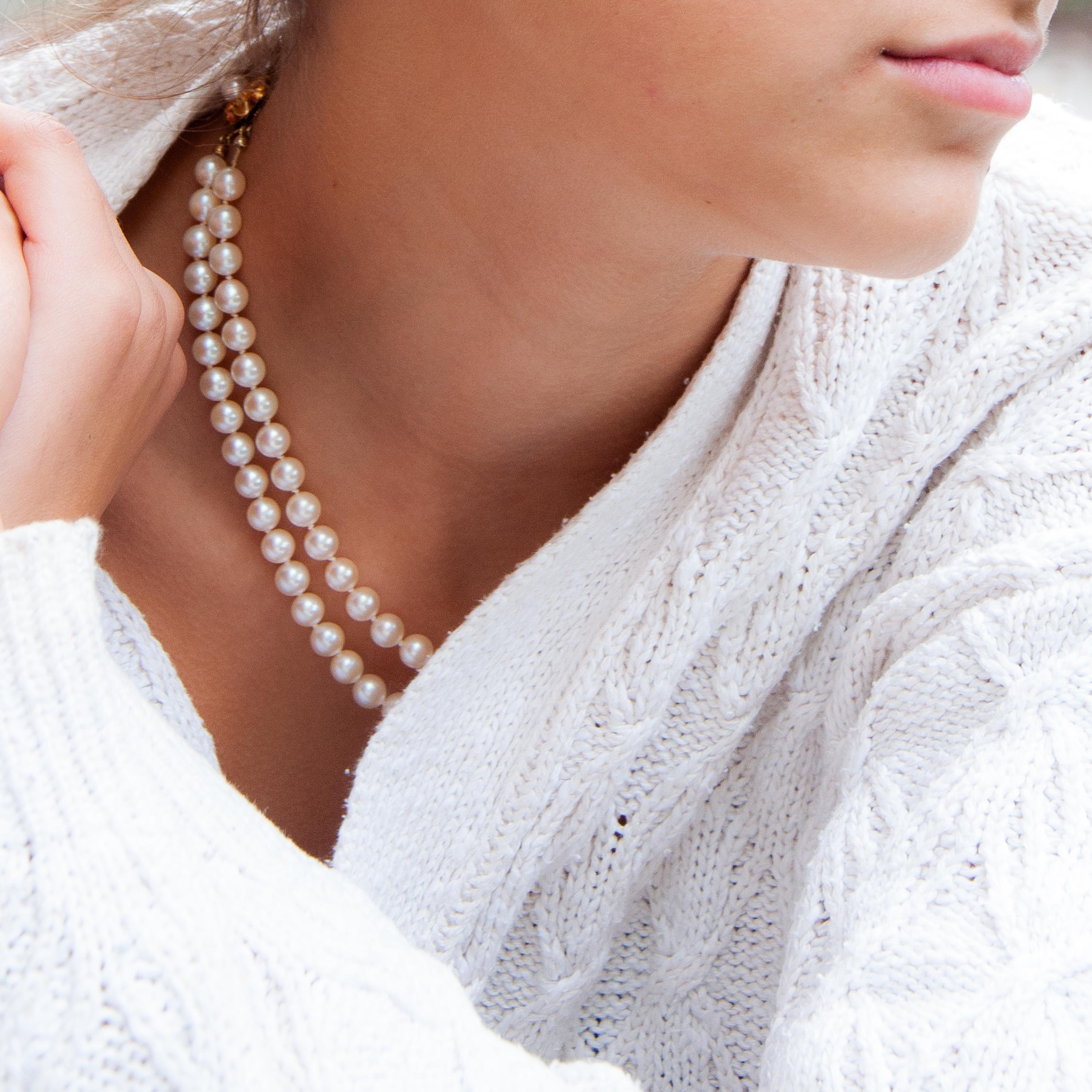 A vintage cultured pearl necklace set with a 14 karat gold clasp. The two-strand necklace is strung with cultured pearls and fastened to a beautiful 14 karat gold clasp. The clasp has a pearl set in the center, while the gold is designed with