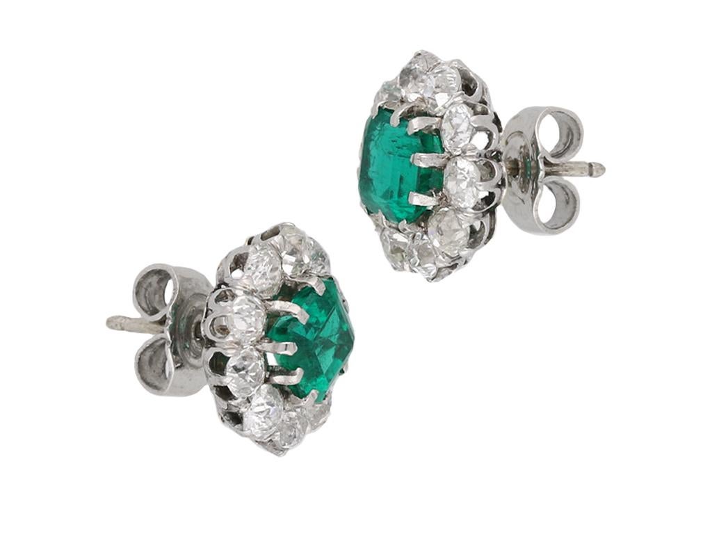 Edwardian Colombian emerald and diamond cluster earrings. A matching pair, each set to centre with an octagonal emerald-cut natural Colombian emerald with no colour enhancement in an open back claw setting, two in total, with an approximate combined
