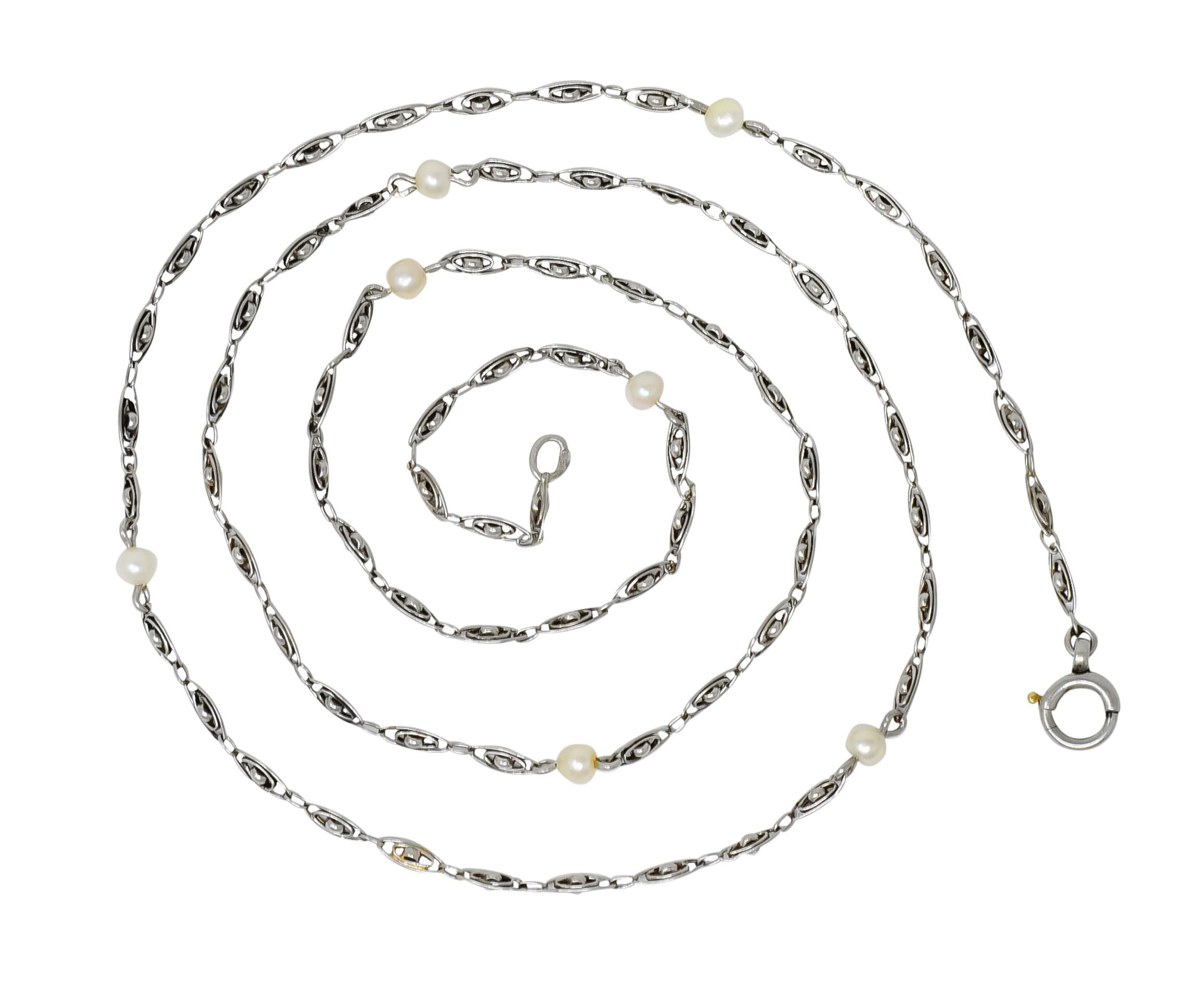 Station style necklace comprised of concentric oval links centering a domed curvature of a perpendicular intersecting rounded link

Accented throughout by seven natural freshwater pearls measuring approximately 3.0 mm with well-matched cream body