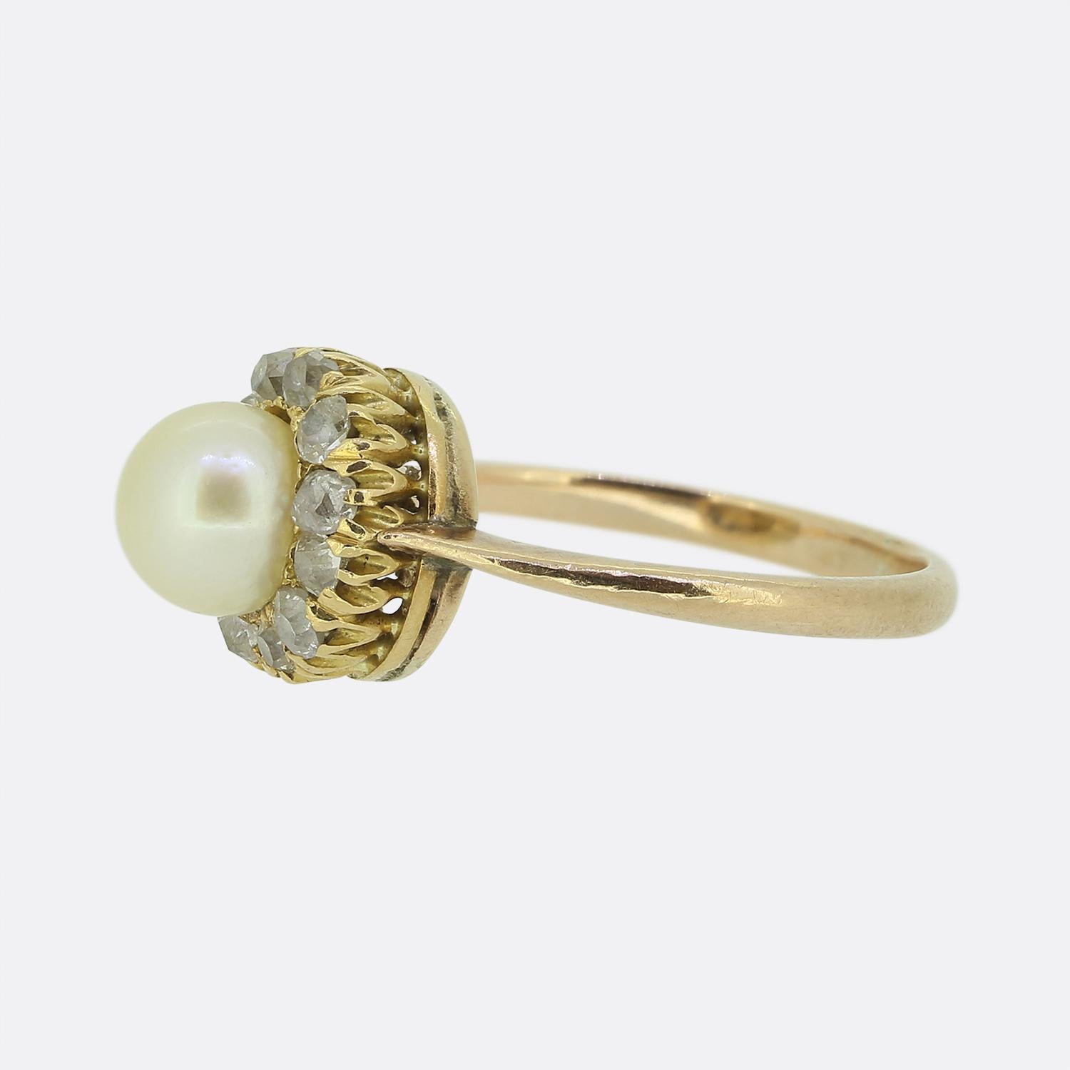 Nous avons ici une bague de style édouardien en perles naturelles et diamants. Cette pièce ancienne en or 18ct présente une perle naturelle ronde de couleur crème au centre de la face, entourée de onze diamants ronds facettés de taille ancienne,