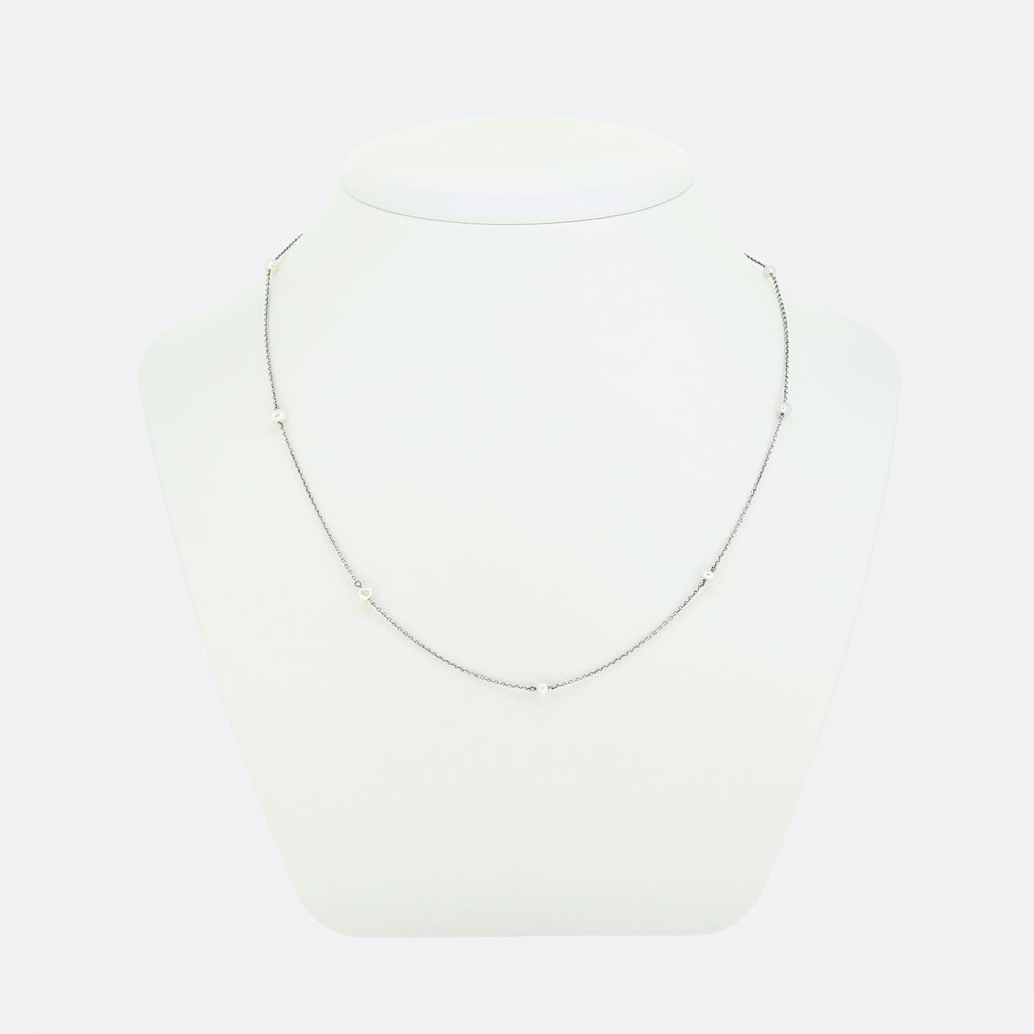 Here we have a refined chain necklace crafted from platinum during the Edwardian period. The design showcases a slim belcher chain interspersed with small, naturally lustrous pearls, creating a subtle yet elegant look. The pearls are evenly spaced,
