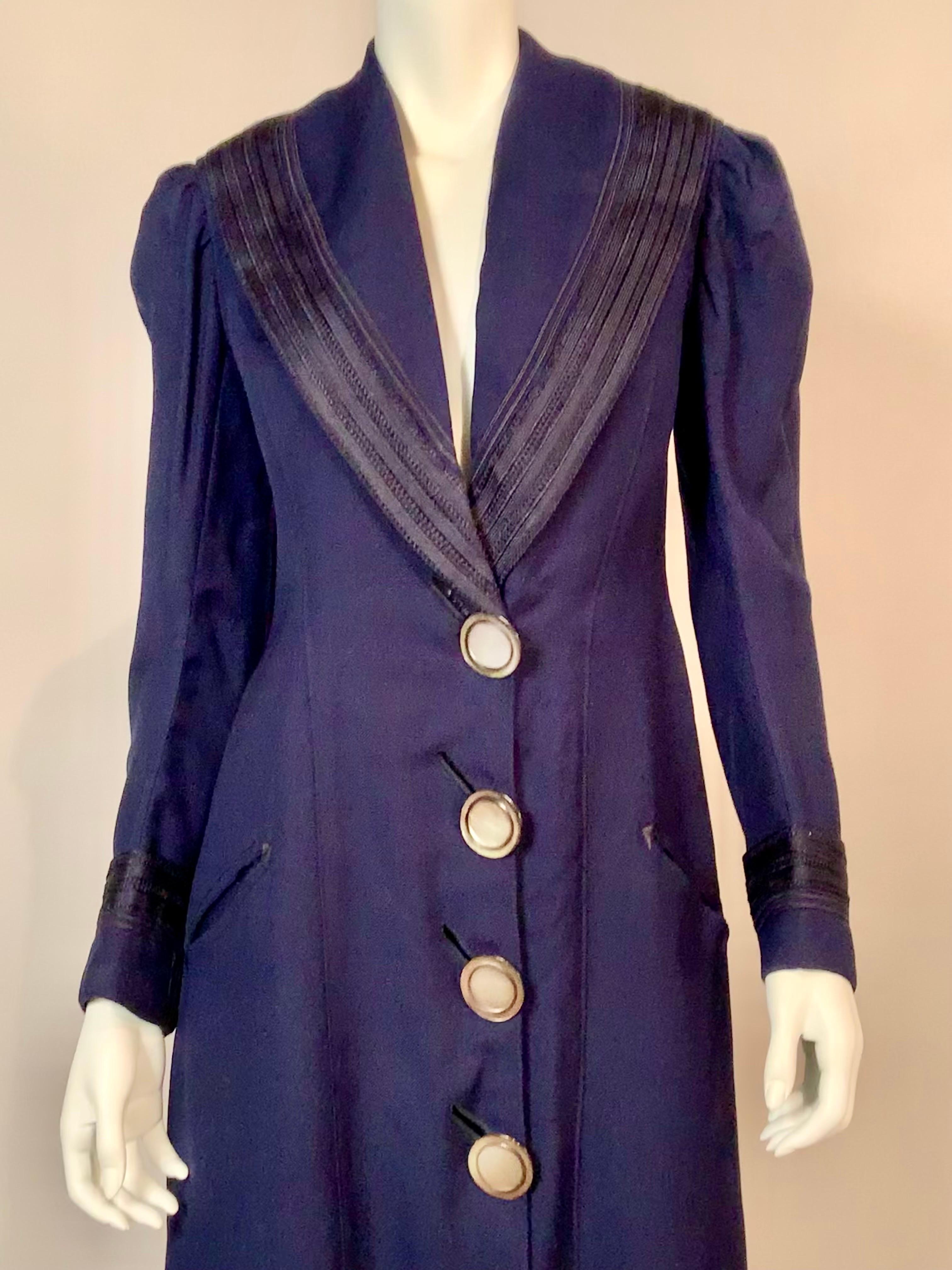 Unlabeled and unlined this chic Edwardian navy blue wool coat has navy blue braid trim on the collar and cuffs.  The slanted pockets have embroidered corners and the four large Mother of Pearl buttons have diagonal button holes.  There are deep