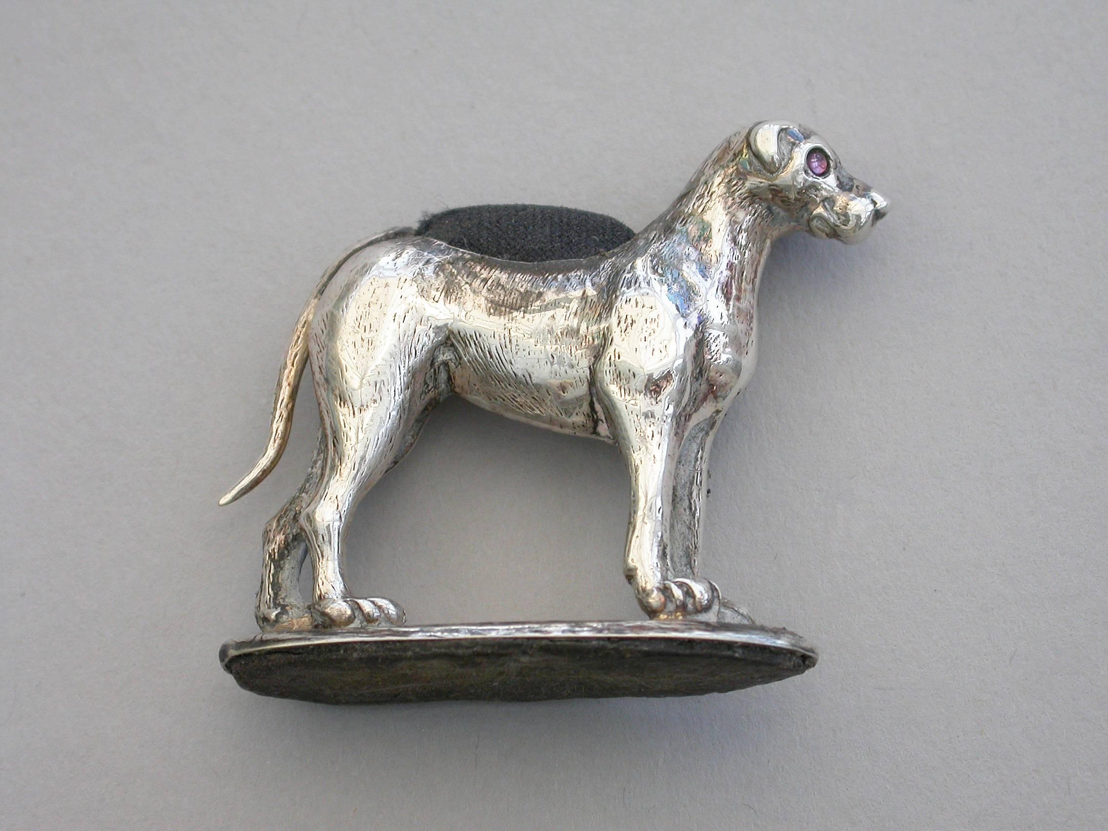 An extremely rare Edwardian novelty silver pin cushion made in the form of a Fox Hound, of small size and standing on an oval base. Complete with original cushion and ruby red glass eyes.

By Adie & Lovekin, Chester, 1909.

In good condition