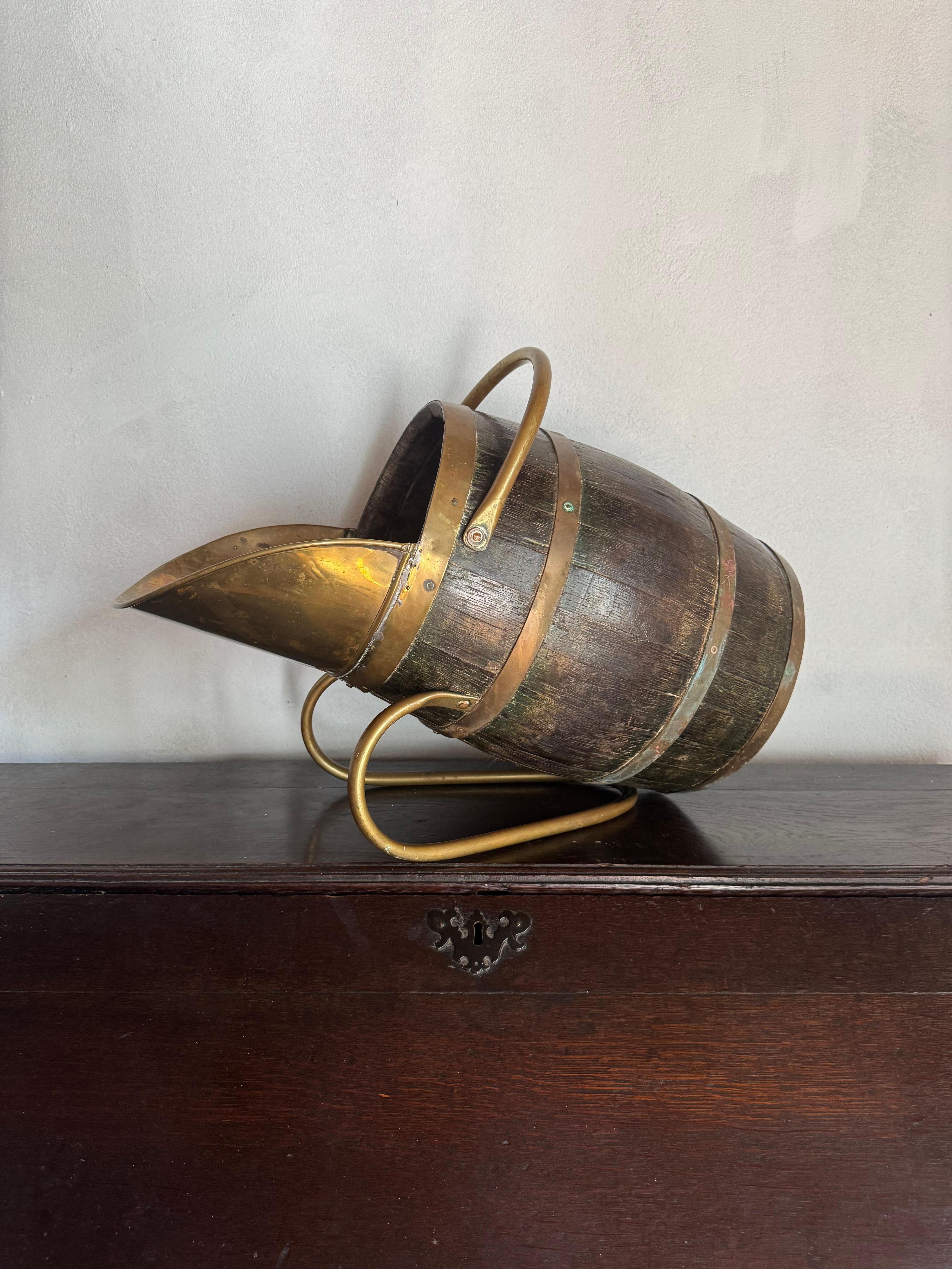 A good oak and brass bound coal scuttle/ wood basket. Very well made with good age and patination. Some wear due to its age but still strong and sturdy.  Very decorative accessory for a fireplace. 