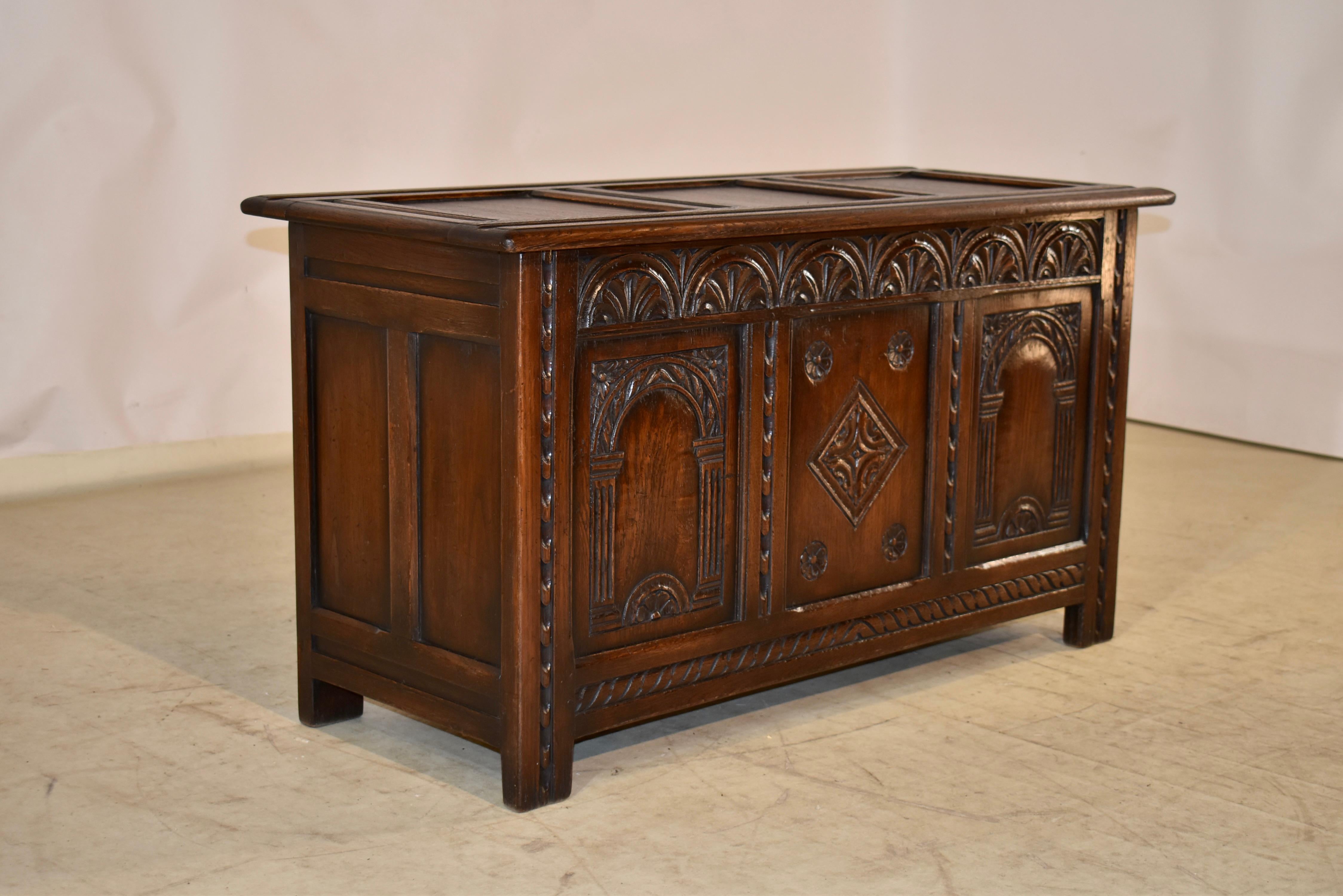 circa 1900-1910 English Edwardian blanket chest from England. The top is paneled, and follows down to paneled sides on all four sides for easy placement in any room. The back and sides feature simple paneling, and the front has a hand carved