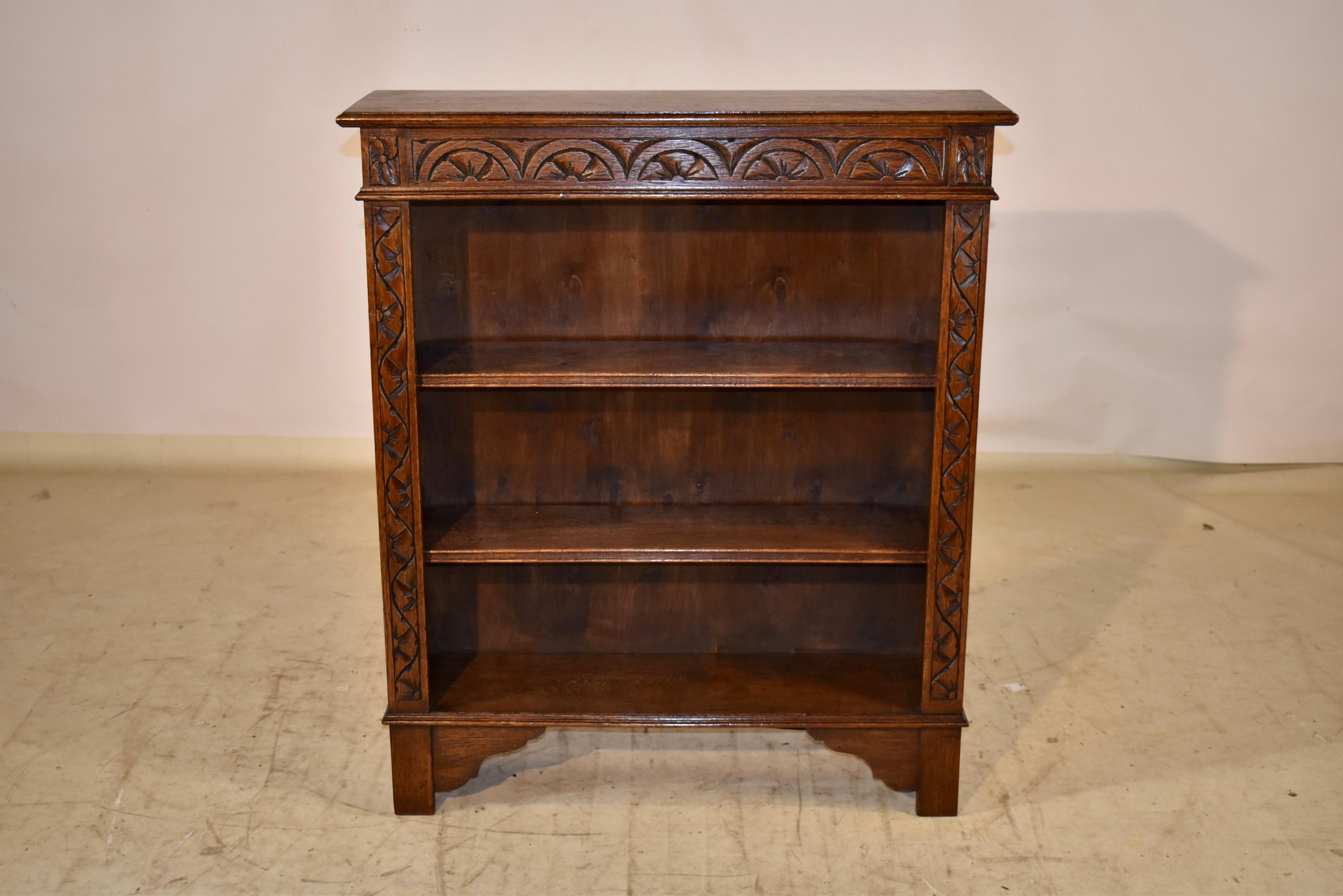 Edwardian oak bookcase from England.  The top has a beveled edge, following down to simple sides and three moveable shelves.  The front of the case has hand carved decoration at the top apron and both sides flanking the shelves.  The case is