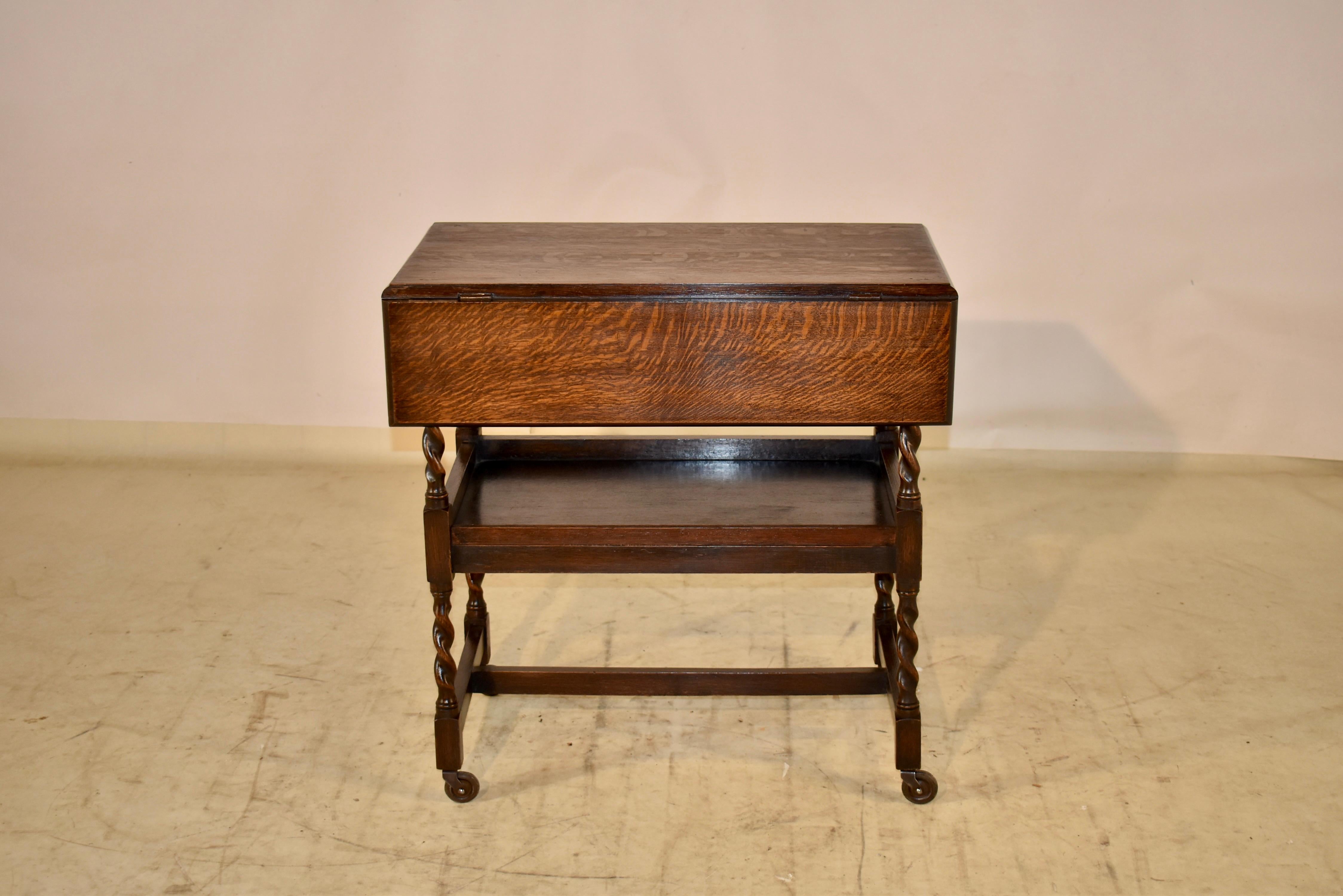 Circa 1900 oak drink cart from England. The top has two leaves and they lift to extend the table to measure 28.63 x 28.88 when the leaves are up. The top has lovely graining and is supported on hand turned barley twist legs, joined by a lower shelf,