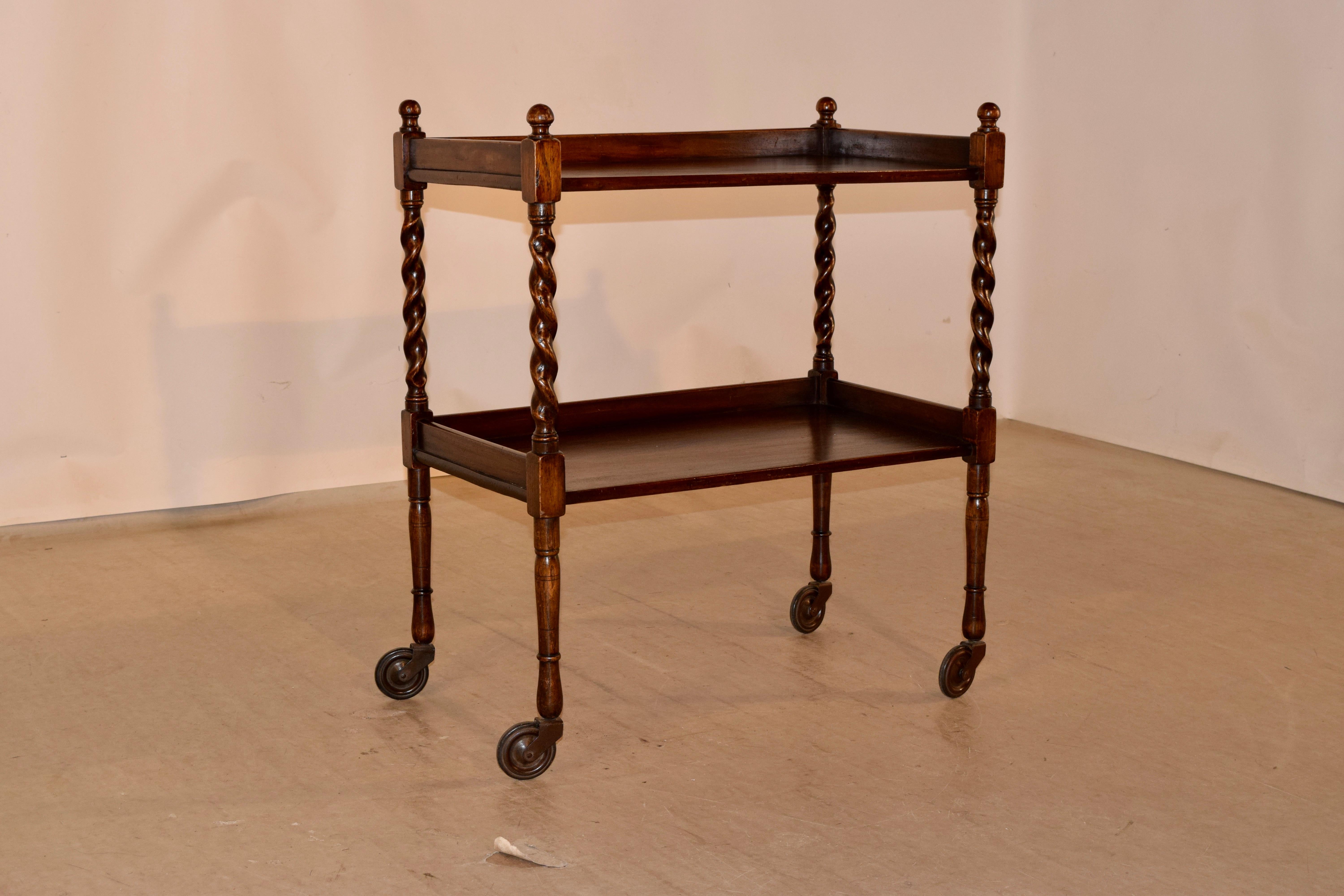 Edwardian drinks cart from England made from oak with two shelves which have galleries on three sides, separated by hand-turned barley twist shelf supports following down to hand-turned legs joined by simple stretchers, terminating in casters.